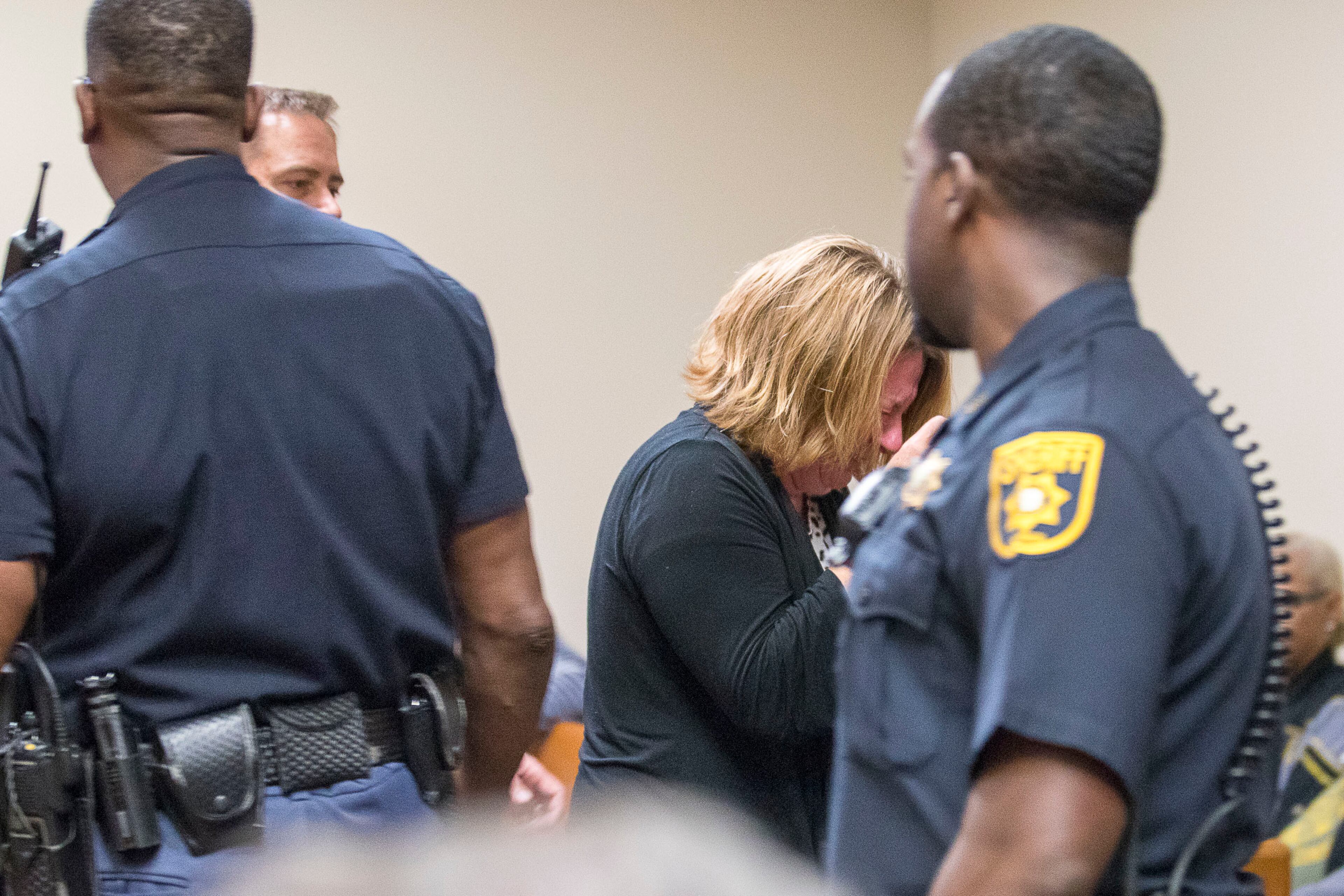 10/14/2019 -- Decatur, Georgia -- Kathy Olsen, wife of Robert "Chip" Olsen, (center) is escorted from the courtroom as she cries aloud while the jury reads the verdict for her husband's trial in front of DeKalb County Superior Court Judge LaTisha Dear Jackson at the DeKalb County Courthouse in Decatur, Monday, October 14, 2019. On the sixth day of jury deliberations the jury found Robert "Chip" Olsen not guilty of felony murder. But jurors reached guilty verdicts on four lesser charges: two counts of violation of oath of office, aggravated assault and making a false statement. (Alyssa Pointer/Atlanta Journal Constitution)