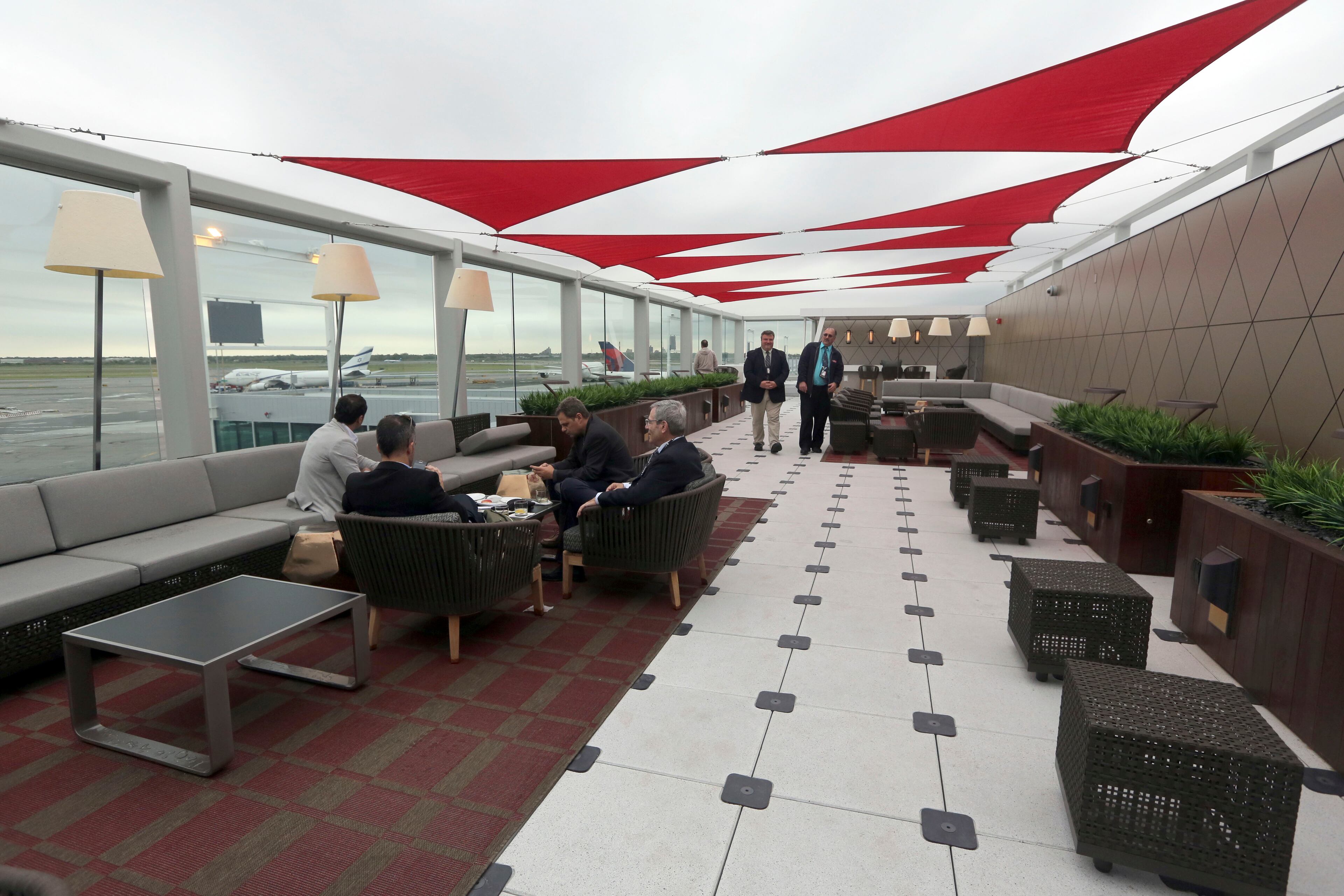 Passengers wait for their flight in the outdoor patio in the Delta Sky club at Kennedy Airport Friday.