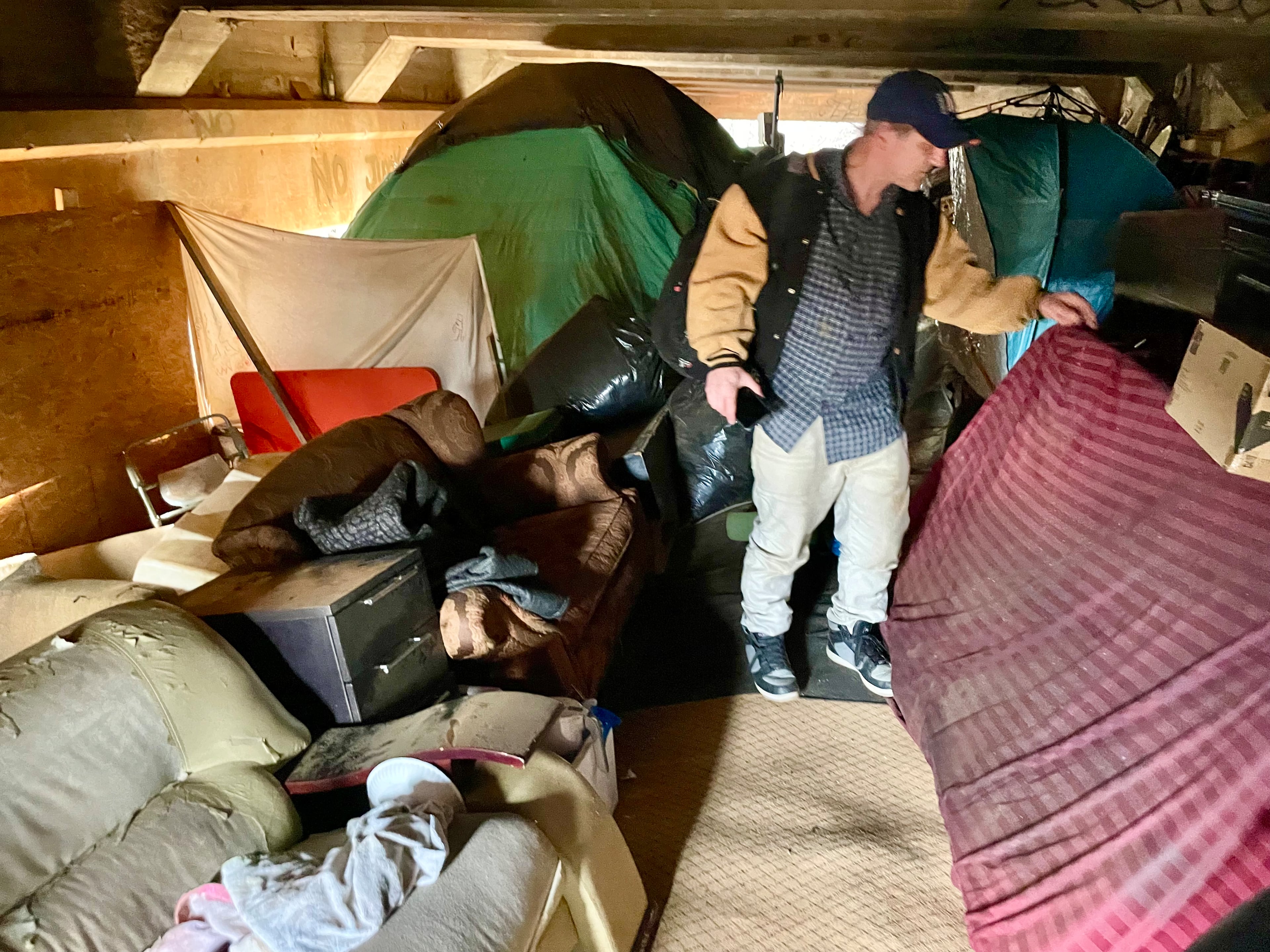 Scott Drotar inspects the interior of an elaborate homeless encampment built under a bridge on Cheshire Bridge. He was looking for a homeless man he had been helping.