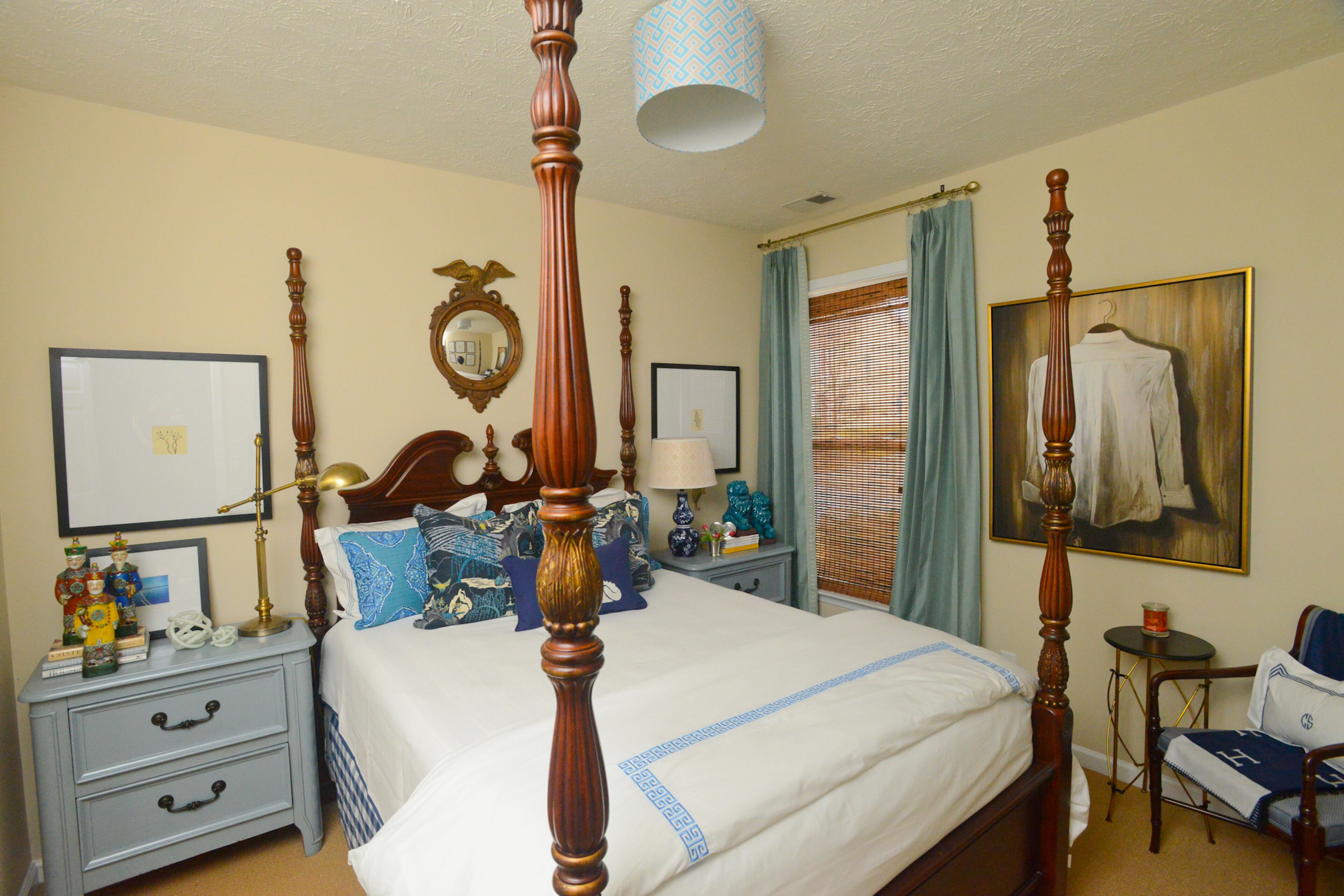 A traditional four-poster bed is flanked by vintage side tables in Travis Snyder's and Craig Cowan's guest bedroom. Snyder, an interior designer, used varying shades of blue, as seen in the lighting, pillows and draperies, as well as traditional accessories like the eagle-framed mirror above the bed, to create a classic preppy look.