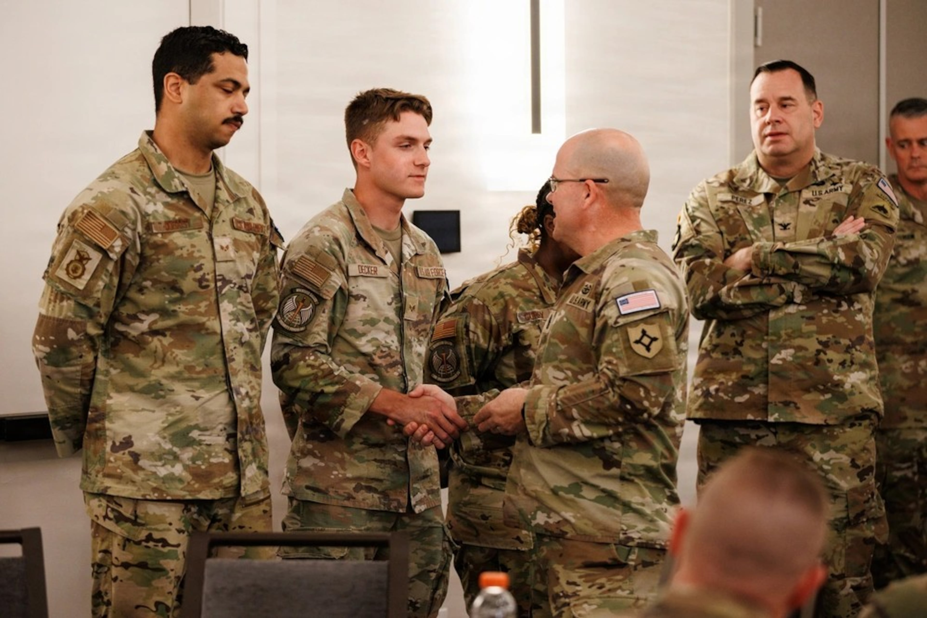 U.S. Army Command Sgt. Maj. Thomas Delano, command sergeant major, Joint Task Force-District of Columbia, awards his coin to Airman 1st Class Jacob Decker, a National Guardsman with the Georgia National Guard, assigned to JTF-DC of Columbia, in support of the DC Safe and Beautiful mission, in Arlington, Virginia, Aug. 19, 2026. (Courtesy of Staff Sgt. Adrianne Lopez/U.S. Army National Guard)