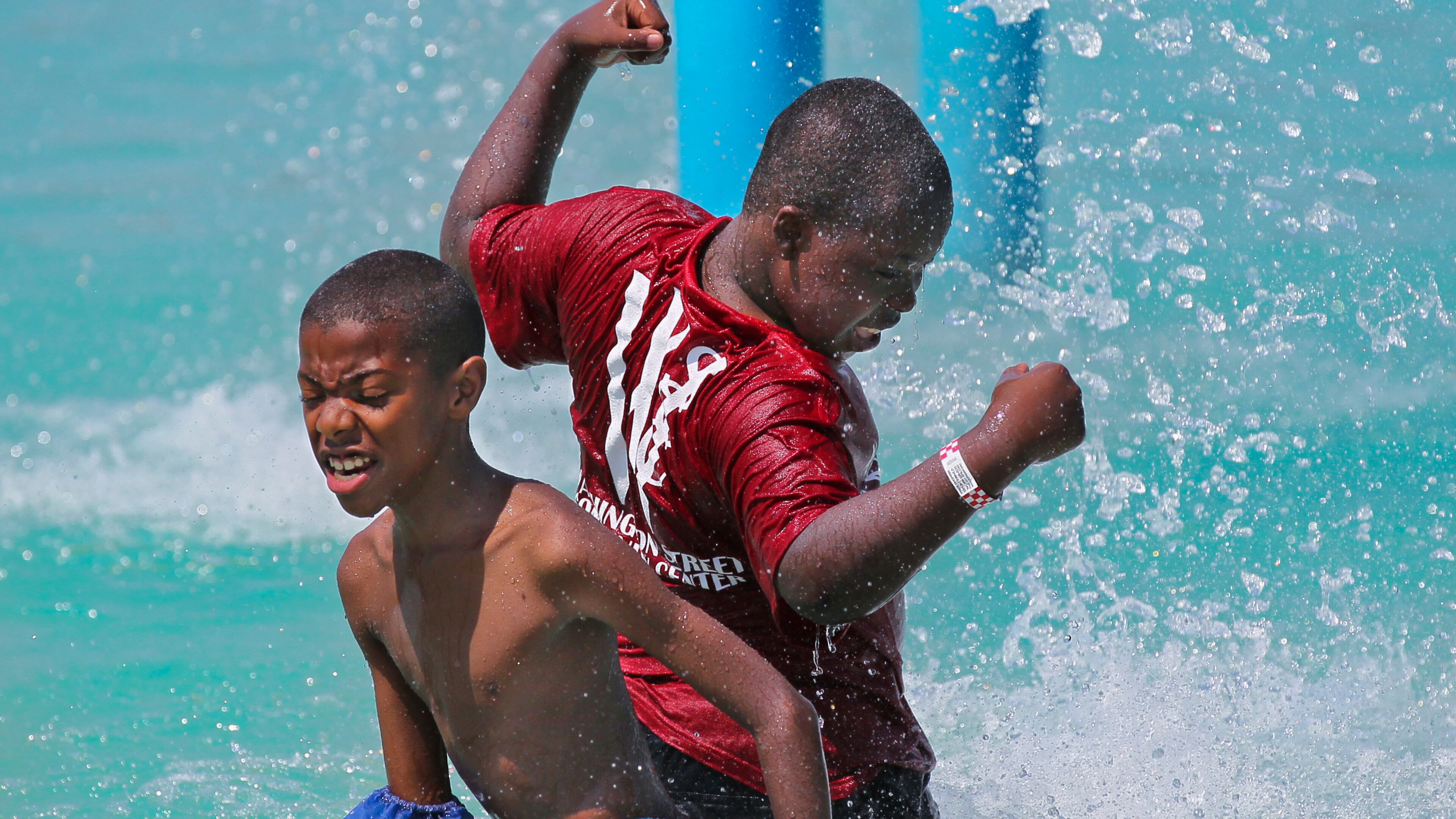 Malik Ambles, left, 11, and Jesse Sands, 12, right, feel the coolness of the water spray at Clayton County International Park in summer 2012. JOHN SPINK / JSPINK@AJC.COM