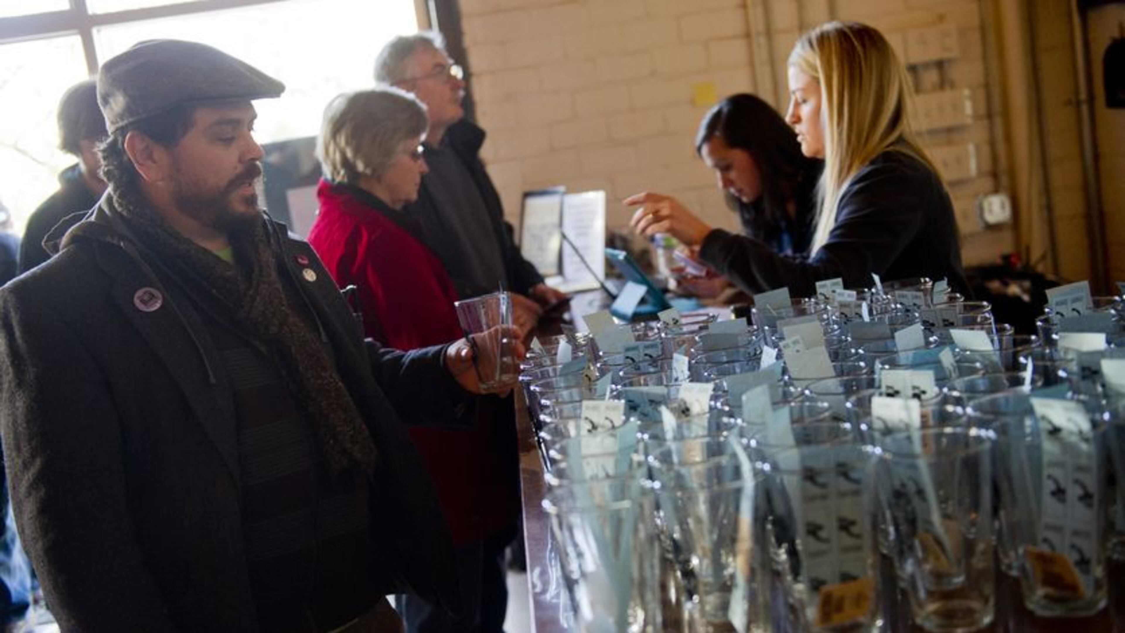 Scott Hutchison (left) grabs his glass and tasting tickets as he enters the Great Southern Craft Beer Competition Kickoff Party at Monday Night Brewing in Atlanta. JONATHAN PHILLIPS / SPECIAL