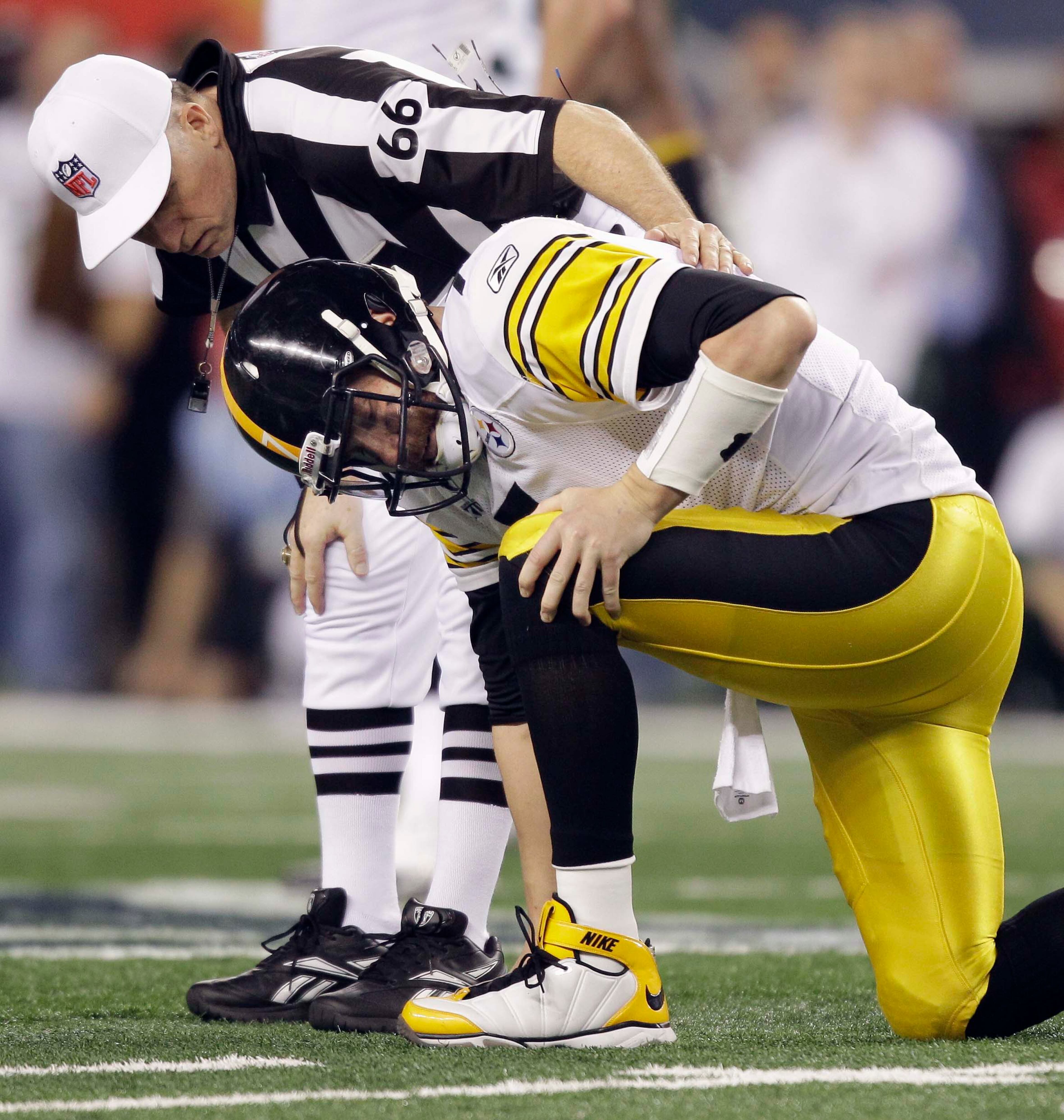 Pittsburgh QB Ben Roethlisberger holds his leg after a play as referee Walt Anderson checks on him during the first half.