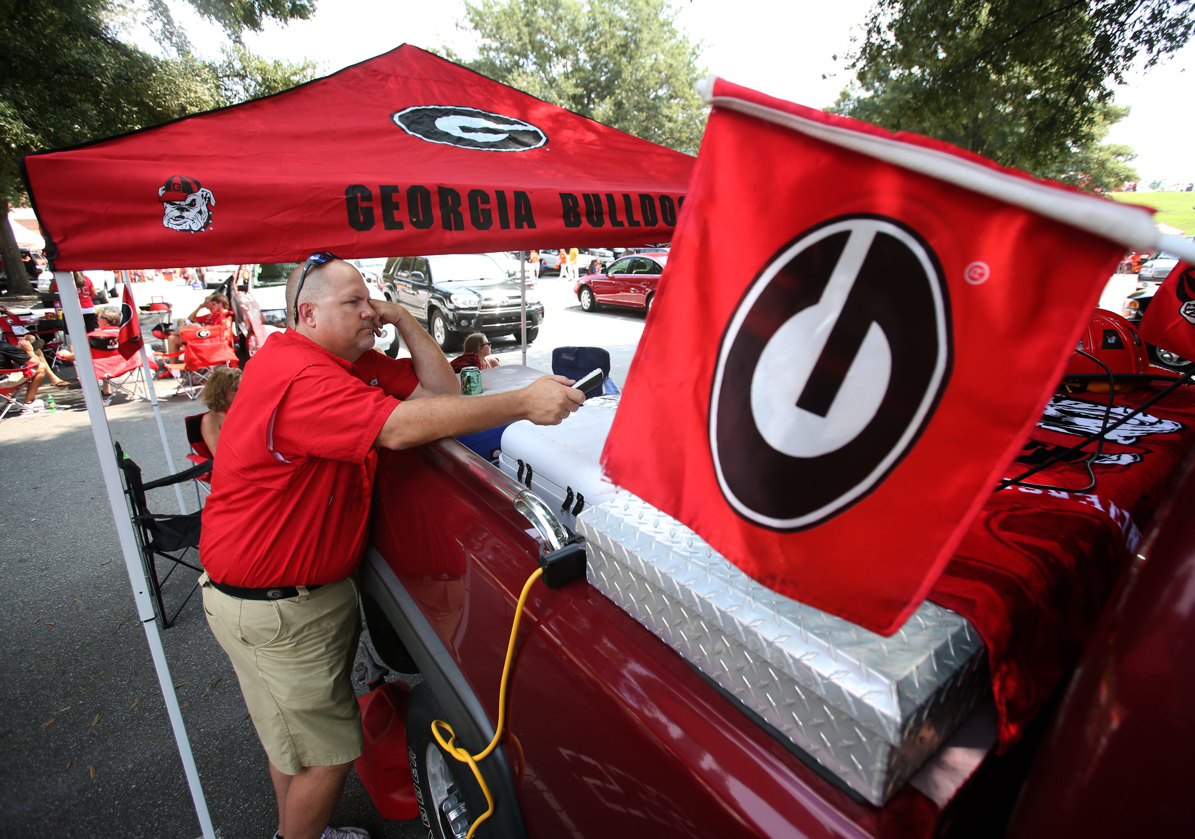 Georgia fan Russ Hawkins, of Anderson, SC, works on setting up a television in his truck bed. JASON GETZ / JGETZ@AJC.COM