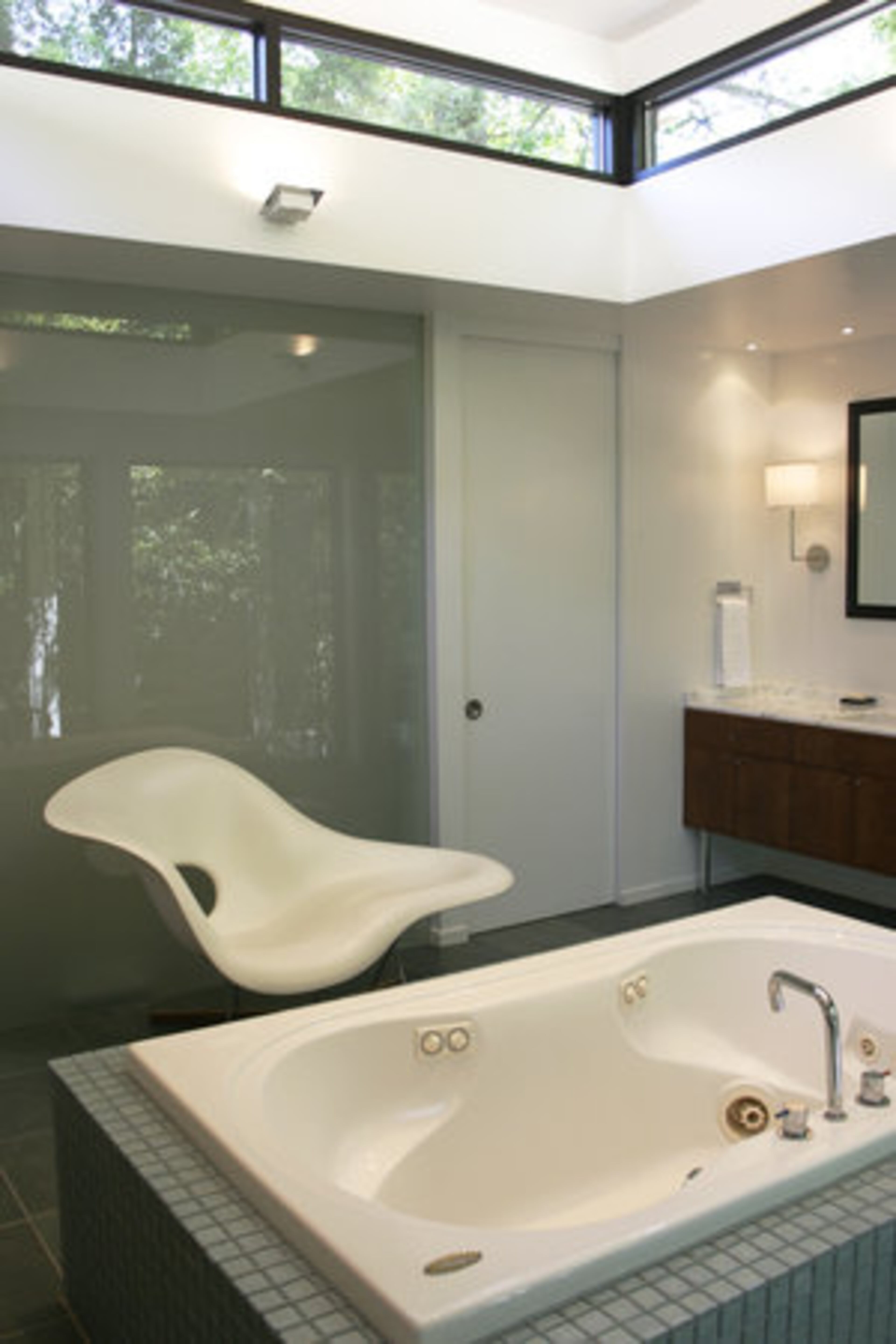 A frosted glass wall partitions the toilet closet within the master bath.