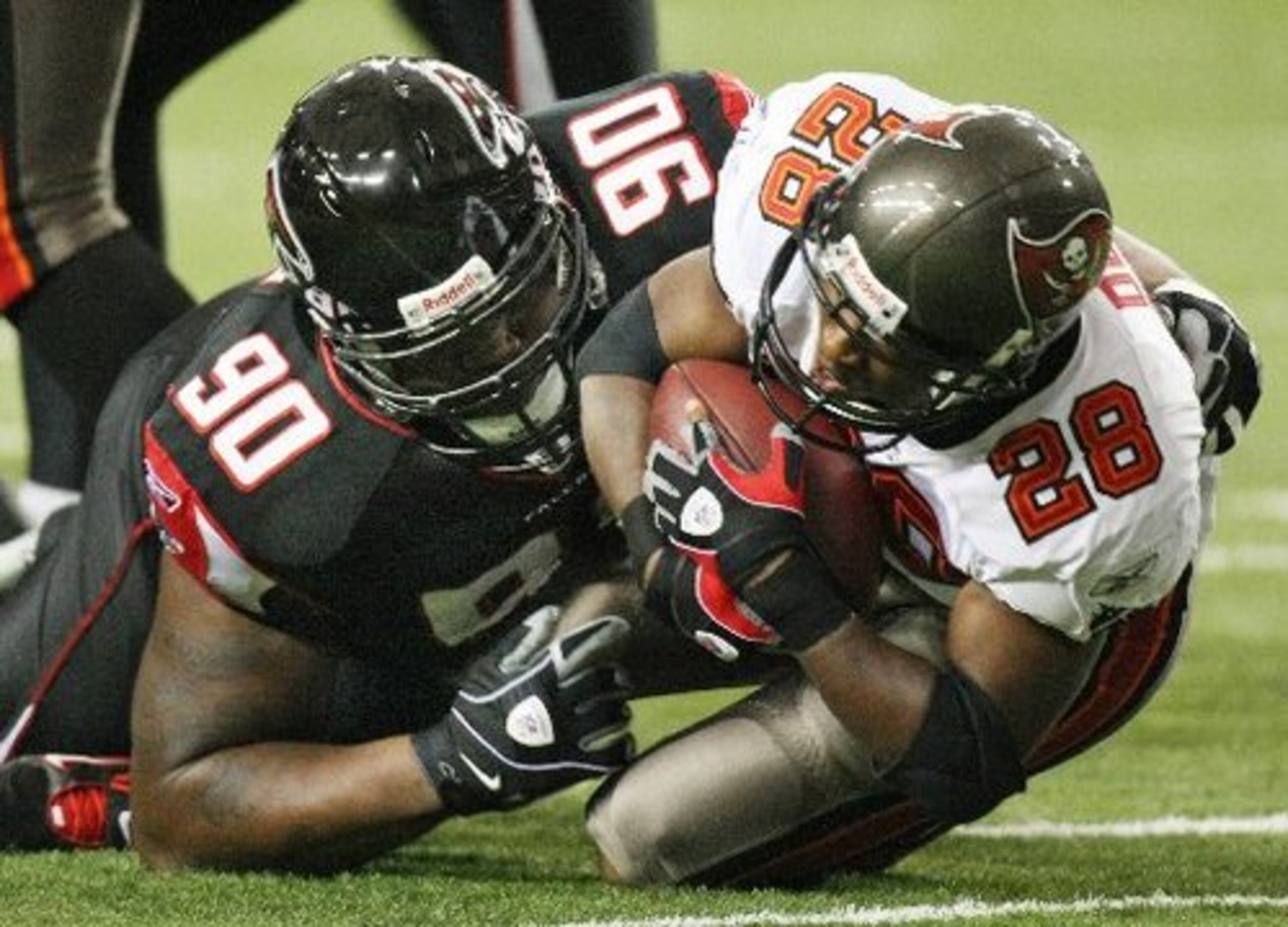 Former Falcon Warrick Dunn is brought down by Grady Jackson after a short gain.