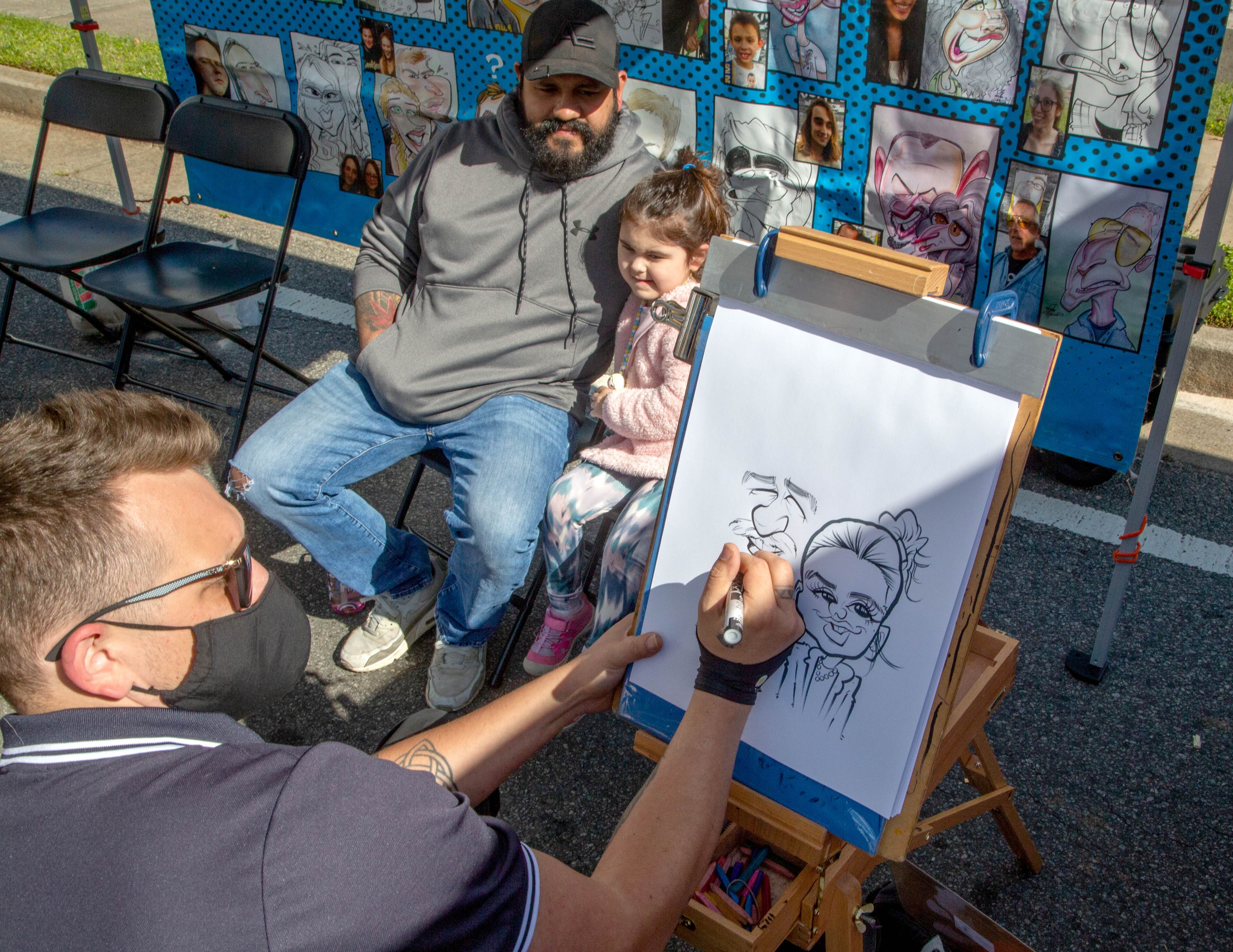 Artist AJ Jansen draws a caricature of two customers at the Acworth Art Fest on Sunday, April 11, 2021. (Photo: Steve Schaefer for The Atlanta Journal-Constitution)