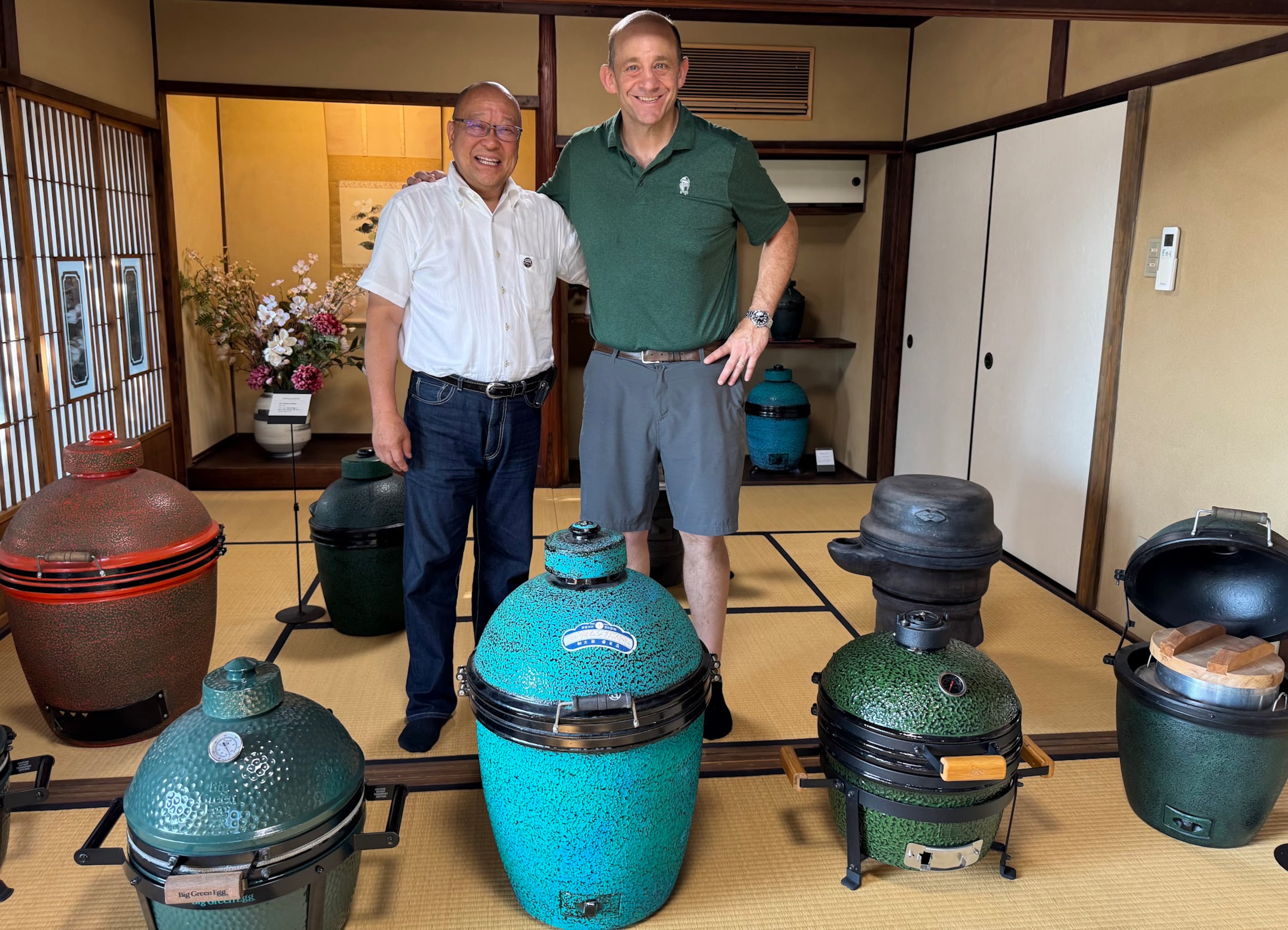 Kamado Q founder Hisashi Kato (left) and Big Green Egg CEO Dan Gertsacov stand together in the tatami-mat gallery at Kamado-an in Nagoya, Japan, surrounded by vintage Japanese mushikamado rice steamers and modern Big Green Egg ceramic grills. (Courtesy of Sam Flemming)