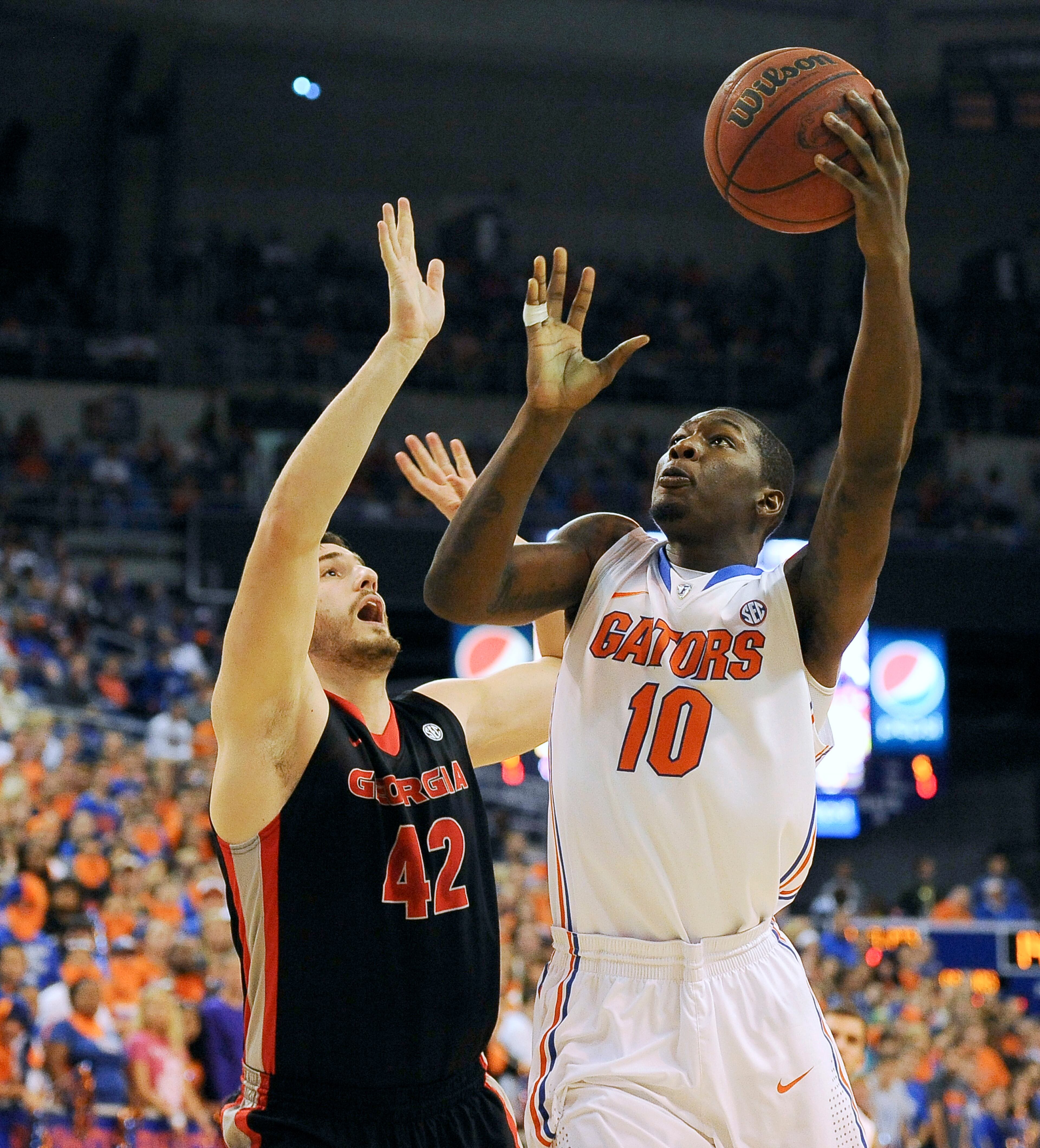 Florida forward Dorian Finney-Smith (10) drives to the basket with Georgia forward Nemanja Djurisic (42) trying to block the shot during the first half of an NCAA college basketball game, Tuesday, Jan. 14, 2014, in Gainesville, Fla.