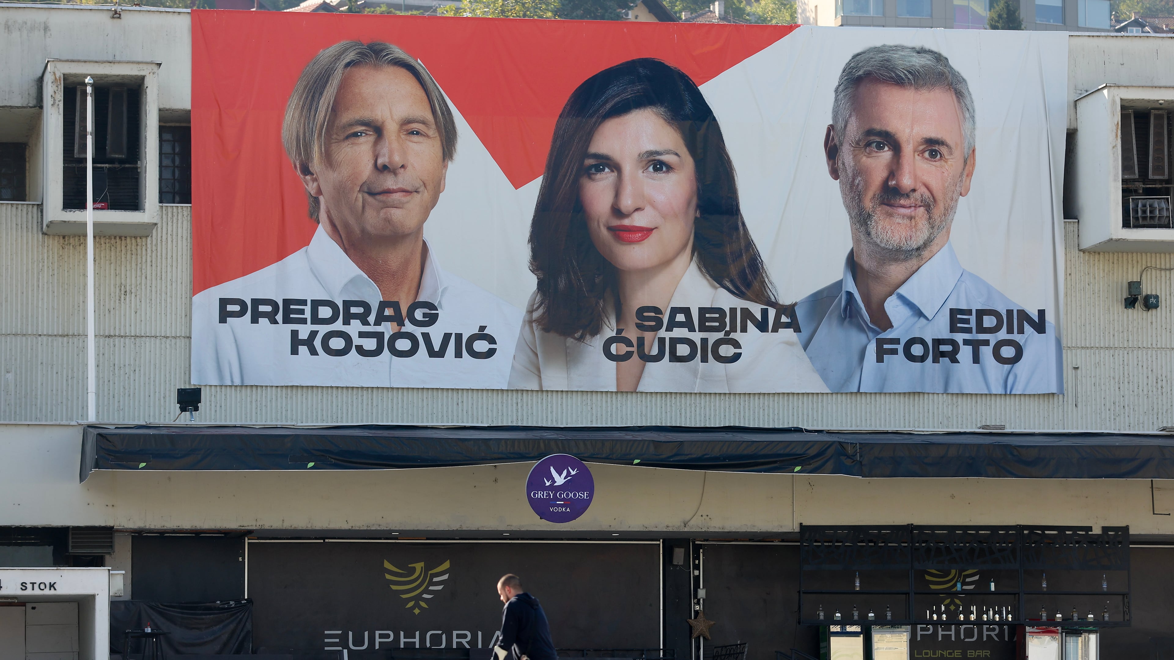 A man walks beneath an election poster featuring Our Party (NS) candidates for the upcoming general elections in Sarajevo, Bosnia, on Sept. 29, 2026. (AP Photo/Armin Durgut)