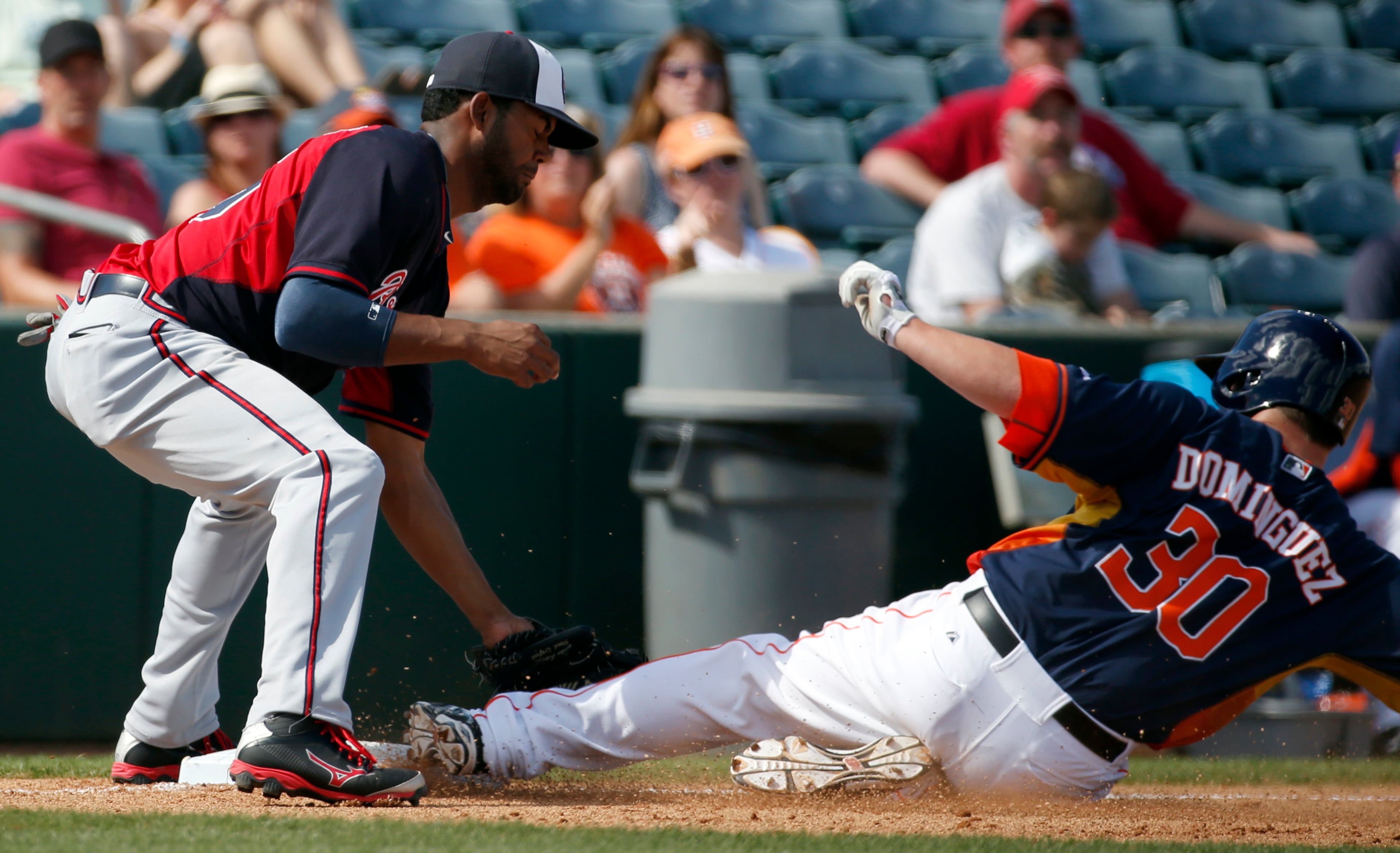 Atlanta Braves shortstop Edward Salcedo, left, cannot make the tag on Houston Astros' Matt Dominguez who is safe at third for a triple in the fourth inning of a spring exhibition baseball game on Sunday, March 2, 2014, in Kissimmee, Fla. The Astros won 7-4. (AP Photo/Alex Brandon)