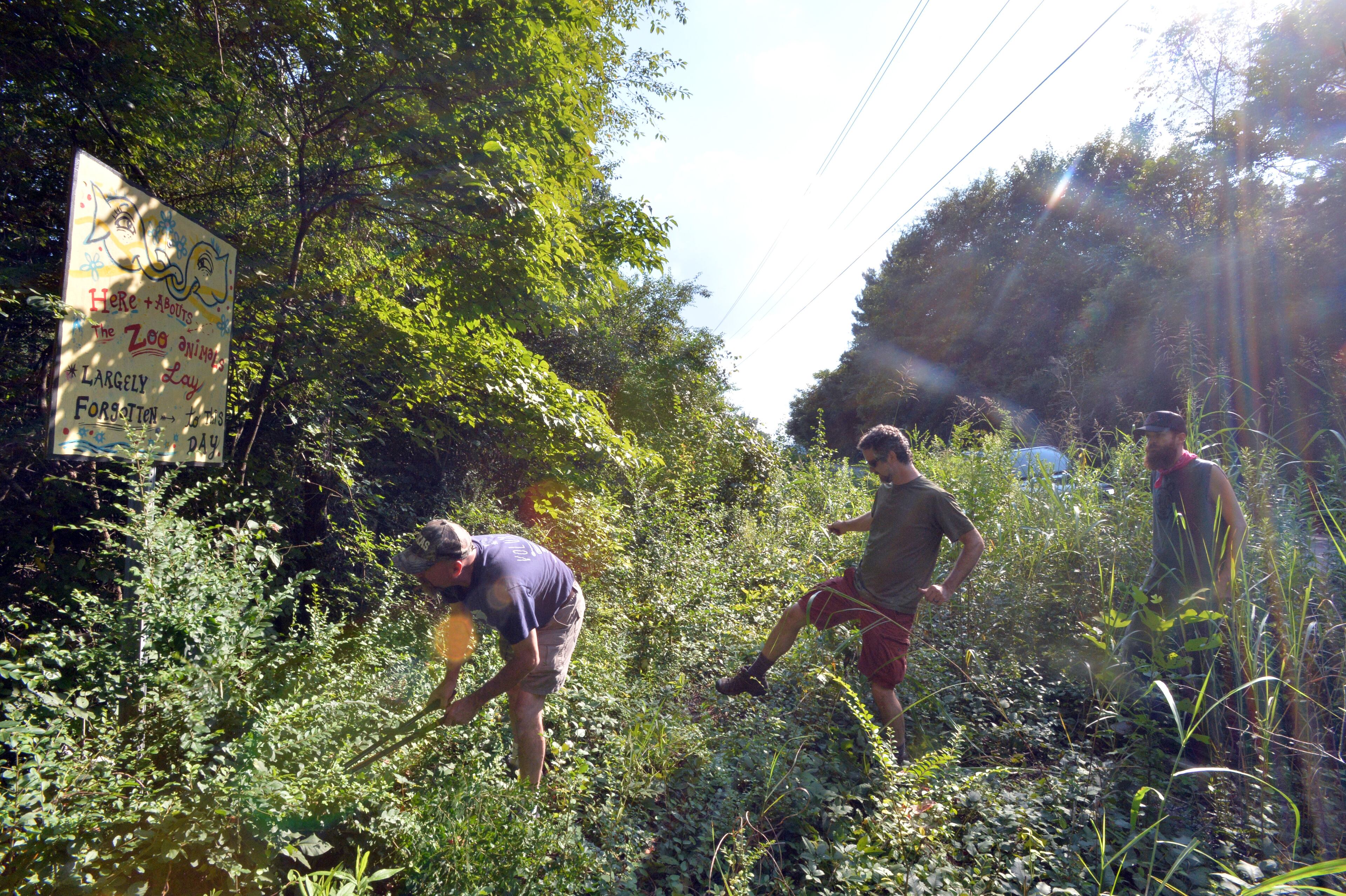 July 29, 2014 Atlanta - Joel Slaton (left), who first started Doll's Head Trail, and his friends Joe Peery (center) and Kyle Brooks visit old zoo burial ground about a mile away from Doll's Head Trail at Constitution Lakes Park on Friday, July 29, 2014. It's called Doll's Head Trail because of many "found art" pieces created with trash, many of it doll heads, that is left over after the South River floods. Personal Journey on Joel Slaton, a carpenter who dealt with being underemployed about three years ago by wandering through on Constitution Lakes Park in Southwest DeKalb. He started picking up garbage that had been dumped off there for years and created a series of whimsical and creepy "found art" pieces, along a literally off-the-beaten path area he dubbed "Doll's Head Trail." HYOSUB SHIN / HSHIN@AJC.COM