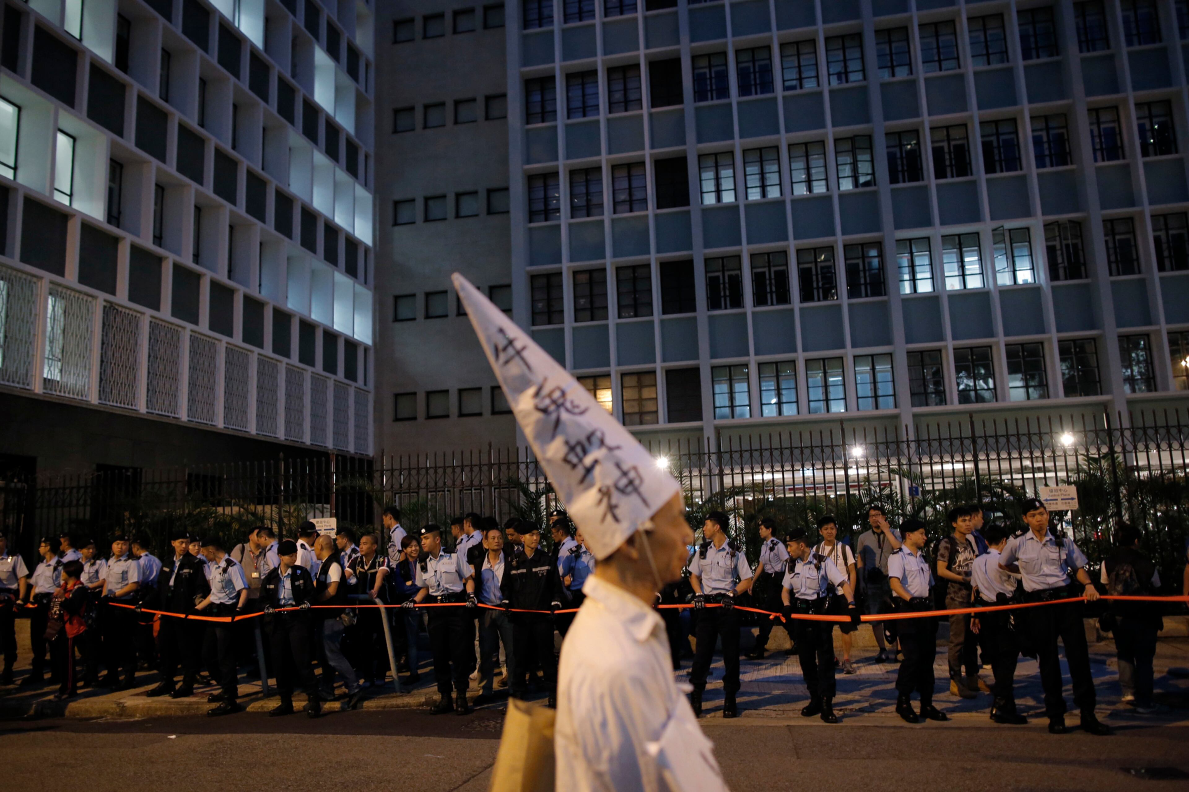 NO DUMB IDEAS--A pro-democracy protester wears a dunce cap to oppose the Cultural Revolution in China as he stands in front of the police officers on the road to the Government House in Hong Kong, Tuesday, May 17, 2016. Hong Kong authorities rolled out a massive security operation on Tuesday as they braced for protests during a top Beijing official's visit to the semiautonomous city, where tensions are rising over Chinese rule. (AP Photo/Kin Cheung)