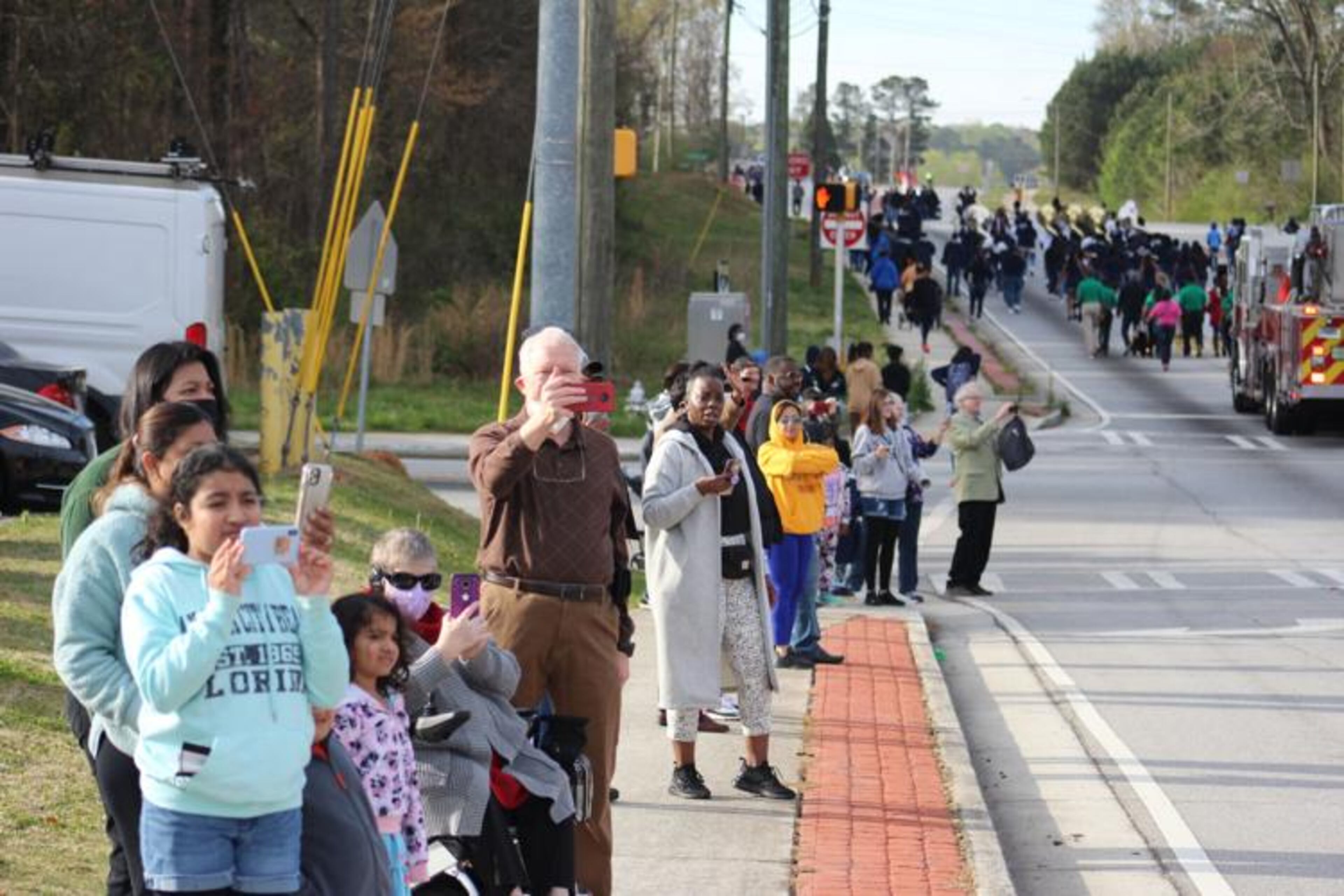 People gather along Floyd Road to watch and film the Taste of Mableton parade as it makes its way to the Mable House complex. (Courtesy of Aleks Gilbert)