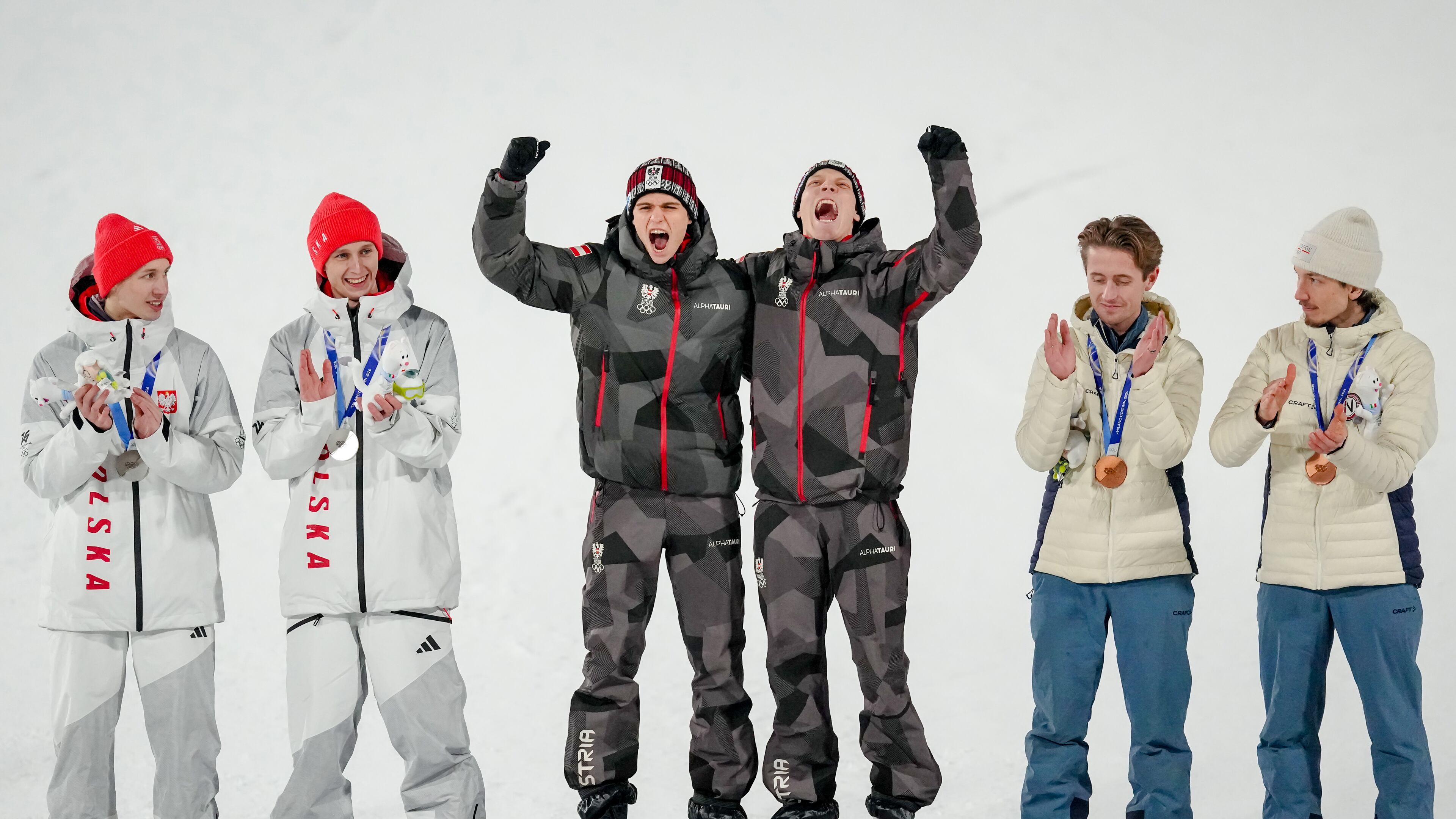 Gold medalists Stephan Embacher and Jan Hoerl, of Austria, celebrate on the podium, with silver medalists Pawel Wasek and Kacper Tomasiak, of Poland, and bronze medalists Kristoffer Eriksen Sundal and Johann Andre Forfang, of Norway, after the ski jumping men's super team competition at the 2026 Winter Olympics, in Predazzo, Italy, Monday, Feb. 16, 2026. (AP Photo/Matthias Schrader)