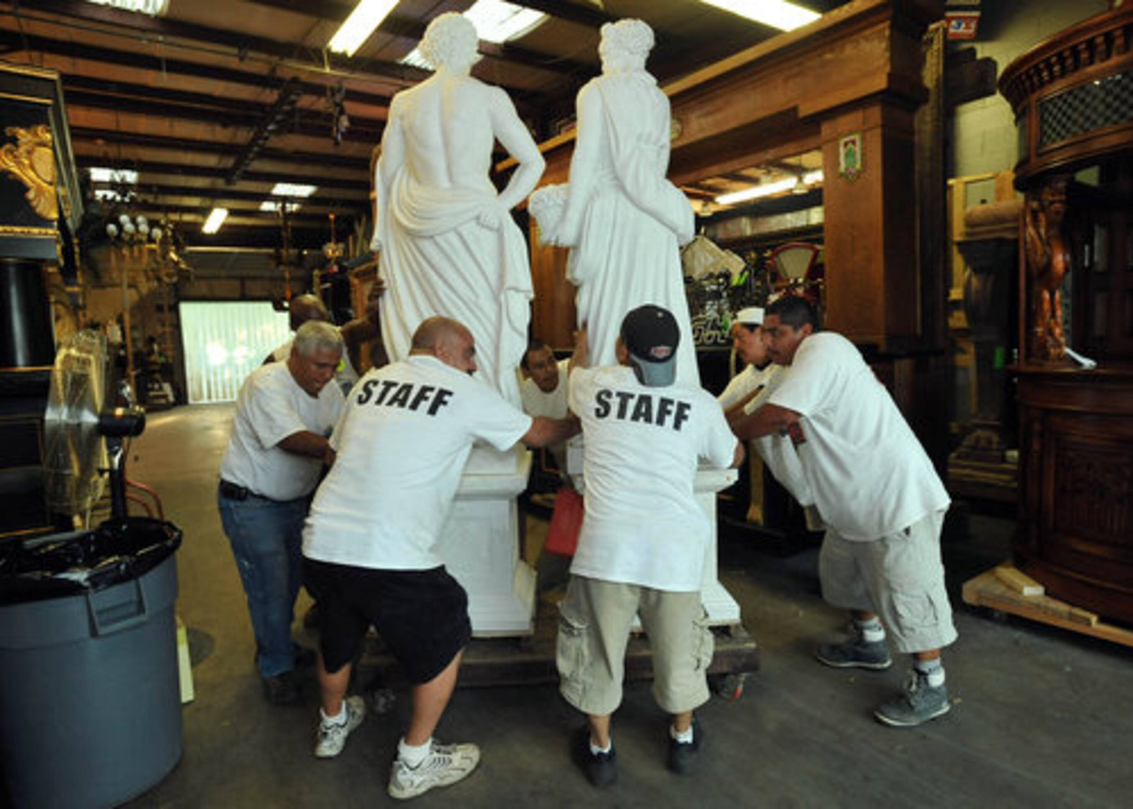 Auction workers move "white marble Four Seasons statues" to a loading area.