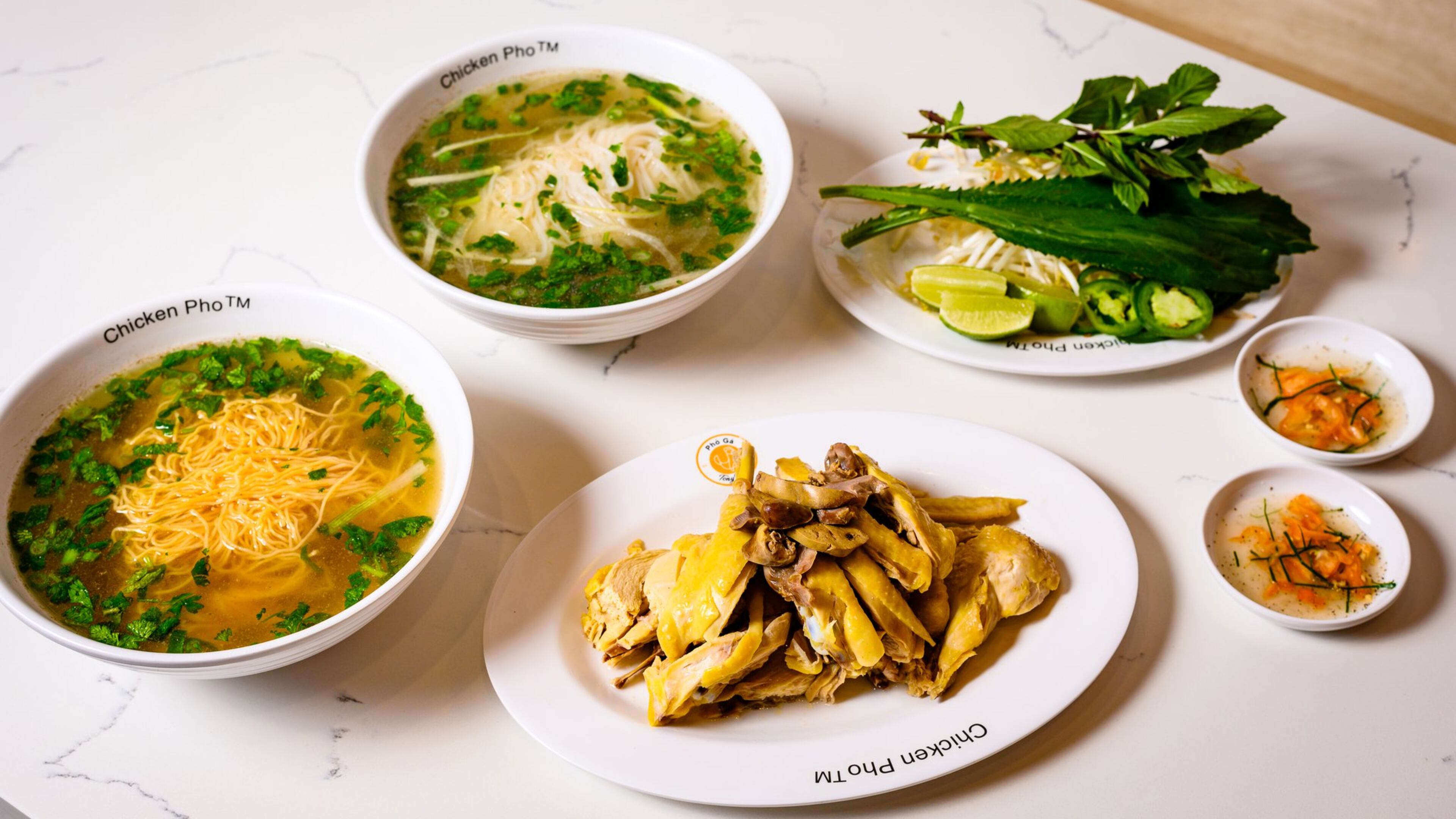 Diners at Pho Ga Tony Tony are served the components to make their pho ga. Here, a half chicken (enough for two people) is shown with egg noodles (left) and rice noodles (top), dipping sauce and a tray of bean sprouts, culantro, basil, sliced raw jalapenos and lime wedges. CONTRIBUTED BY HENRI HOLLIS