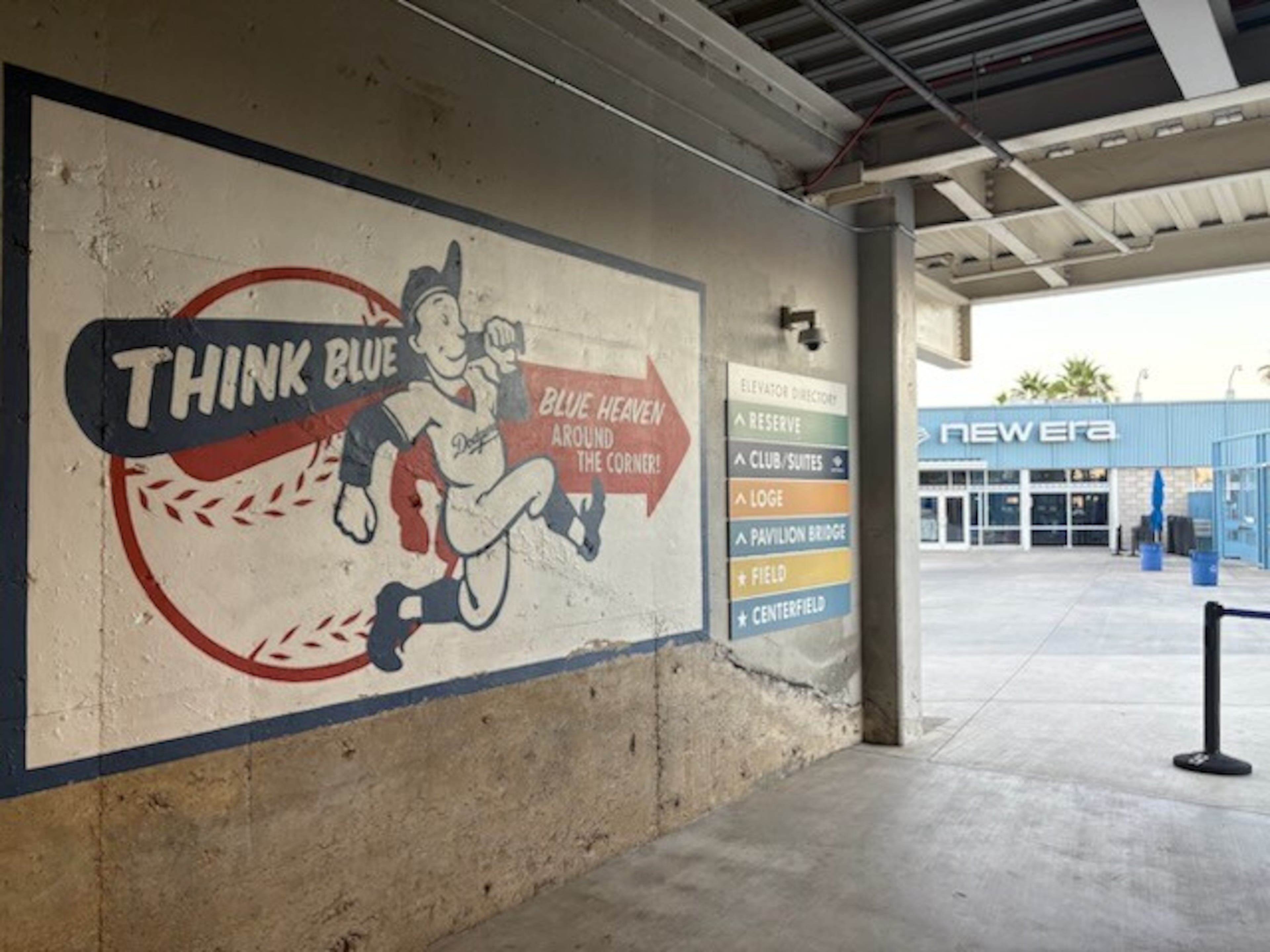 A painted sign in Dodger Stadium with "think blue" written on one of the bats across a player's shoulder followed by a red arrow that reads "Blue heaven around the corner." (Ken Sugiura/AJC)