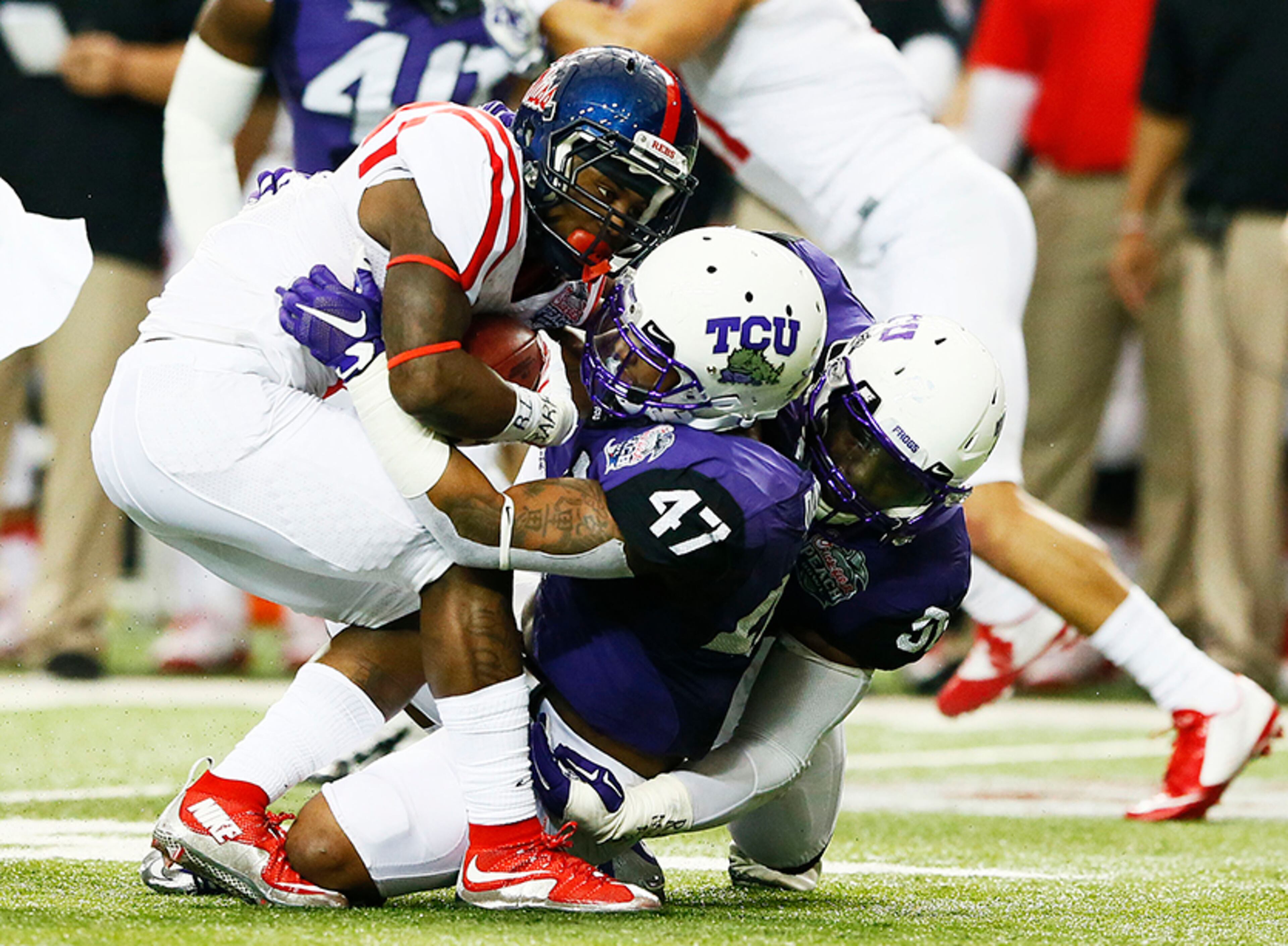 Rebels' Jaylen Walton is tackled by Chucky Hunter (96) and Paul Dawson (47) of the TCU Horned Frogs in the first half during the Chik-fil-A Peach Bowl Wednesday, Dec. 31, 2014, at Georgia Dome in Atlanta.
