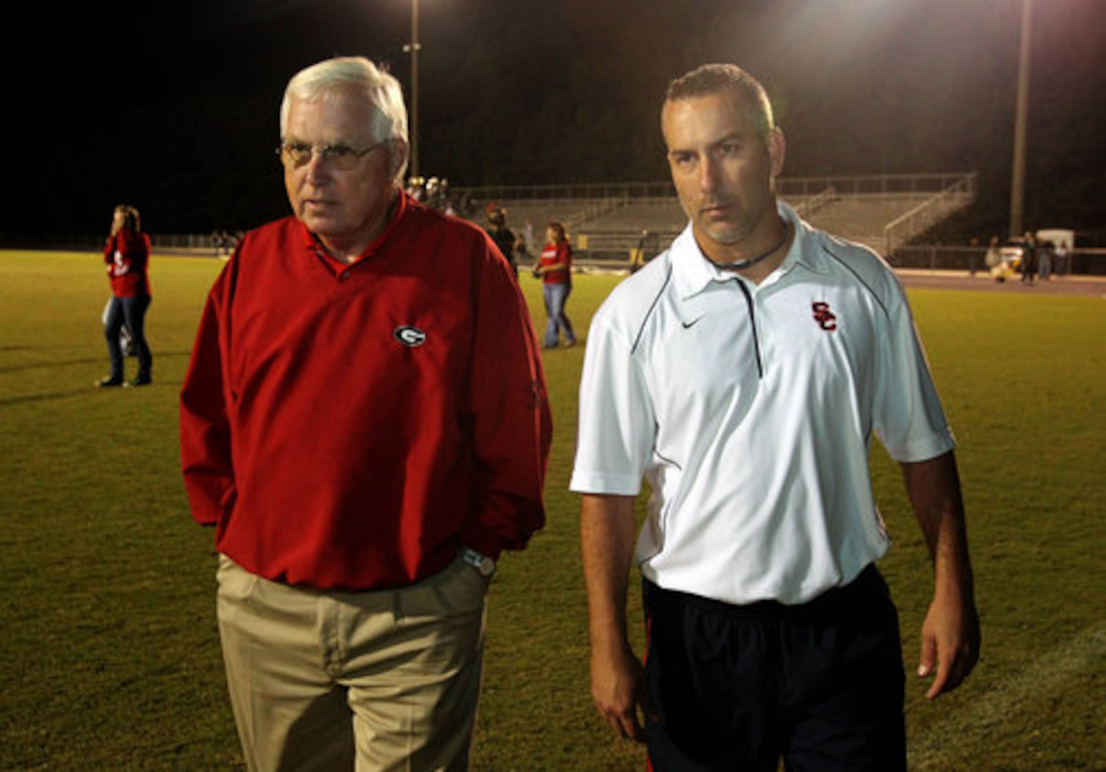 Former Sandy Creek coach Rodney Walker (left) walks off the field with his son, Sandy Creek coach Chip Walker, after their win over Eastside on Friday, Oct. 1, 2010, in Tyrone. The Walkers became the first father-son coaches to win state championships. (Jason Getz/AJC)