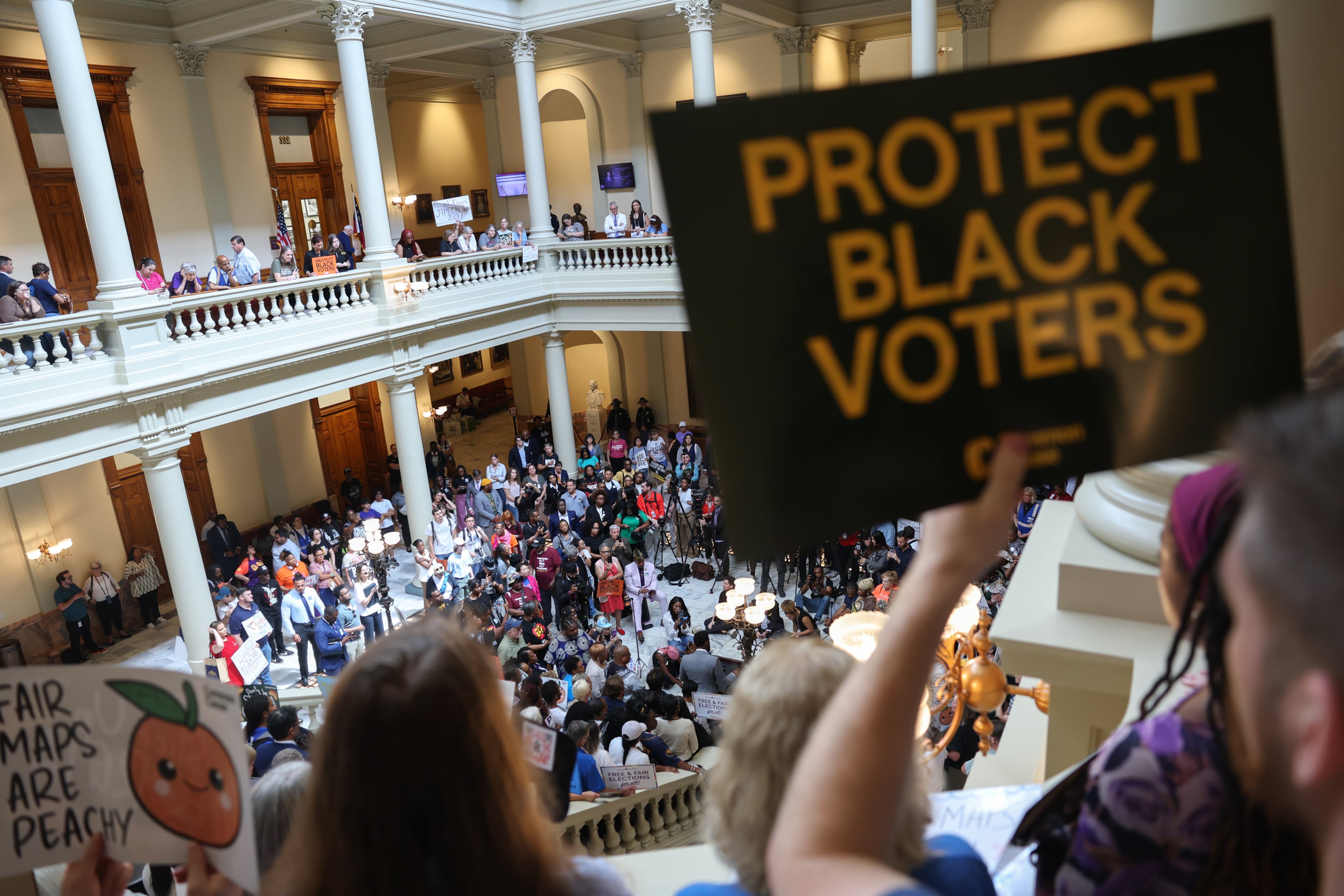 An activist holds a “Protect Black Voters” sign at a press conference before the state legislature convenes for a special session in Atlanta on June 17, 2026. (Arvin Temkar/AJC)