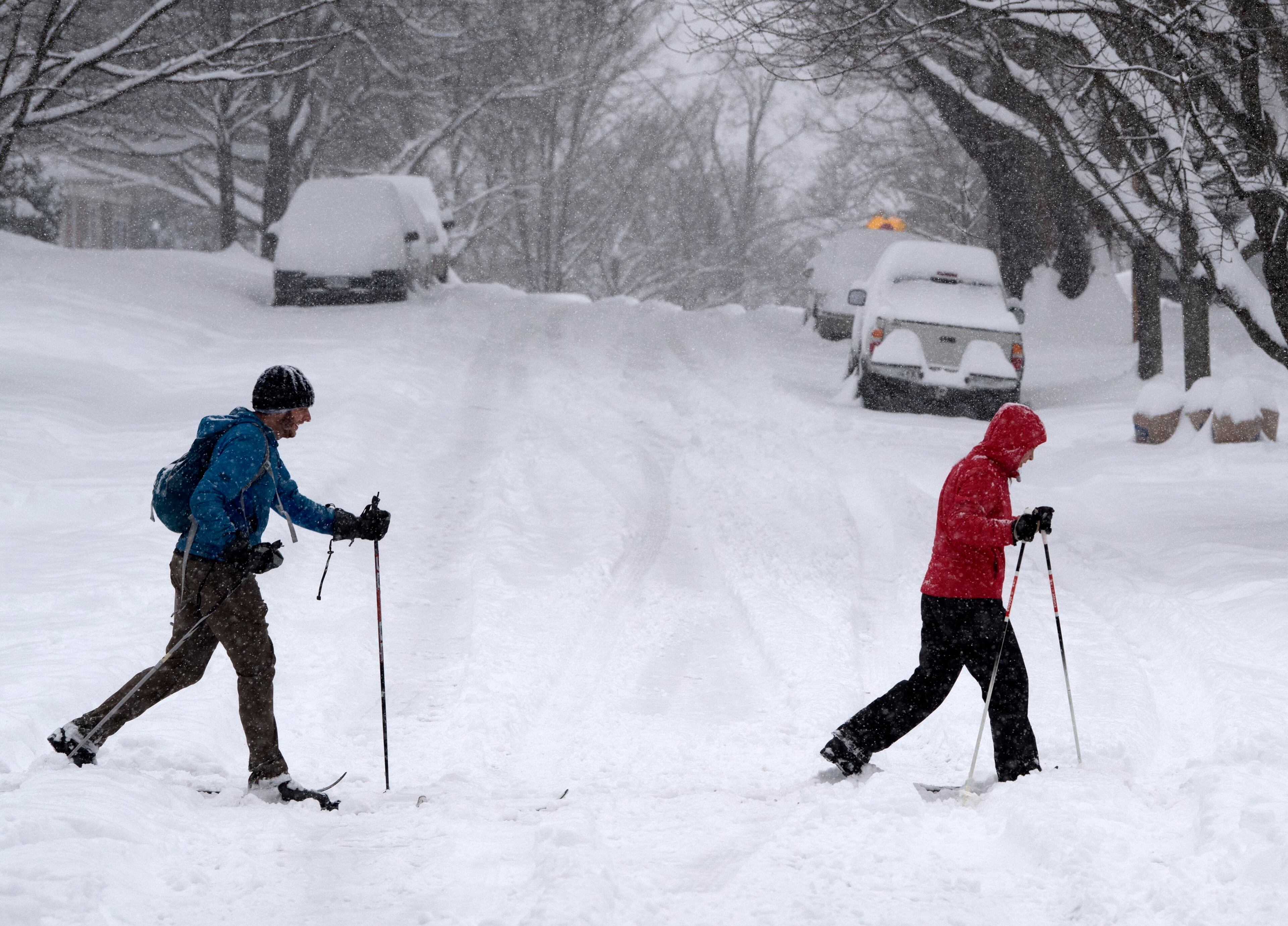 Greg Jans, left, and Stacey Hash get in some cross county skiing in their southwest city neighborhood in Roanoke, Va., Sunday, Dec. 9, 2018. Snow continues to fall in southwest Virginia. (AP Photo/Don Petersen)