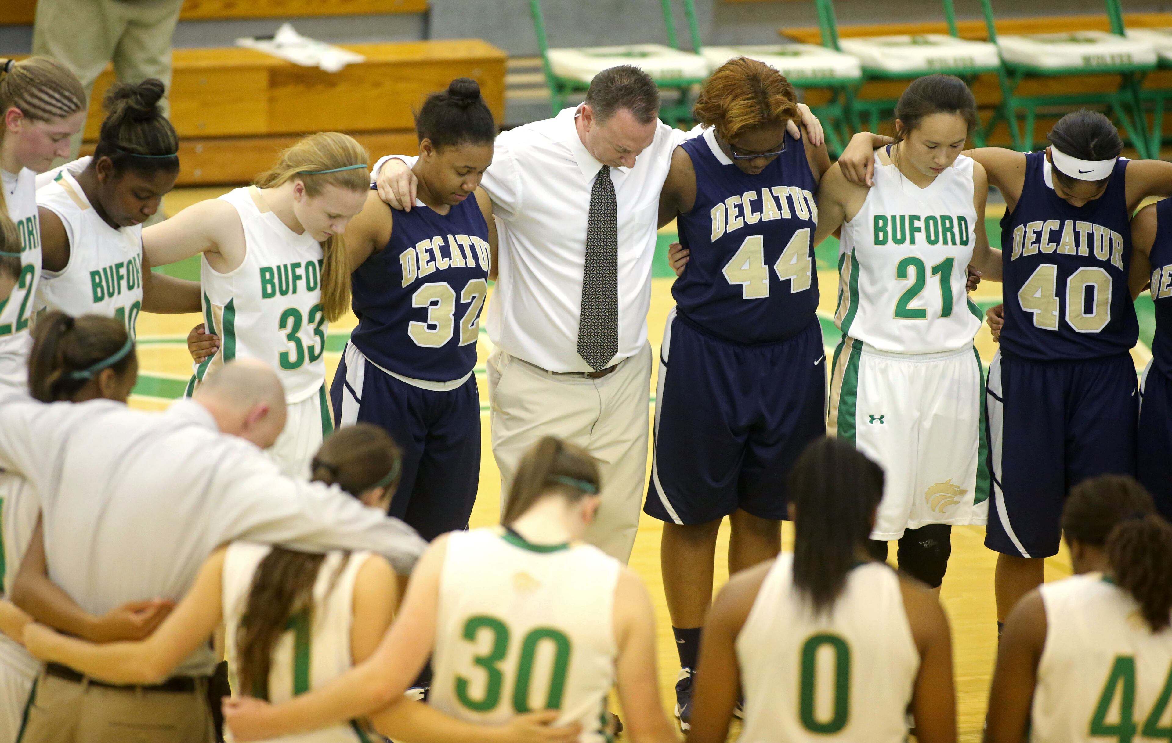 Buford coach Gene Durden (with tie) prays with Buford and Decatur teammates following their game Monday night in Buford. Buford defeated Decatur 41-28 in the second round of the Class AAA state basketball tournament. JASON GETZ / SPECIAL