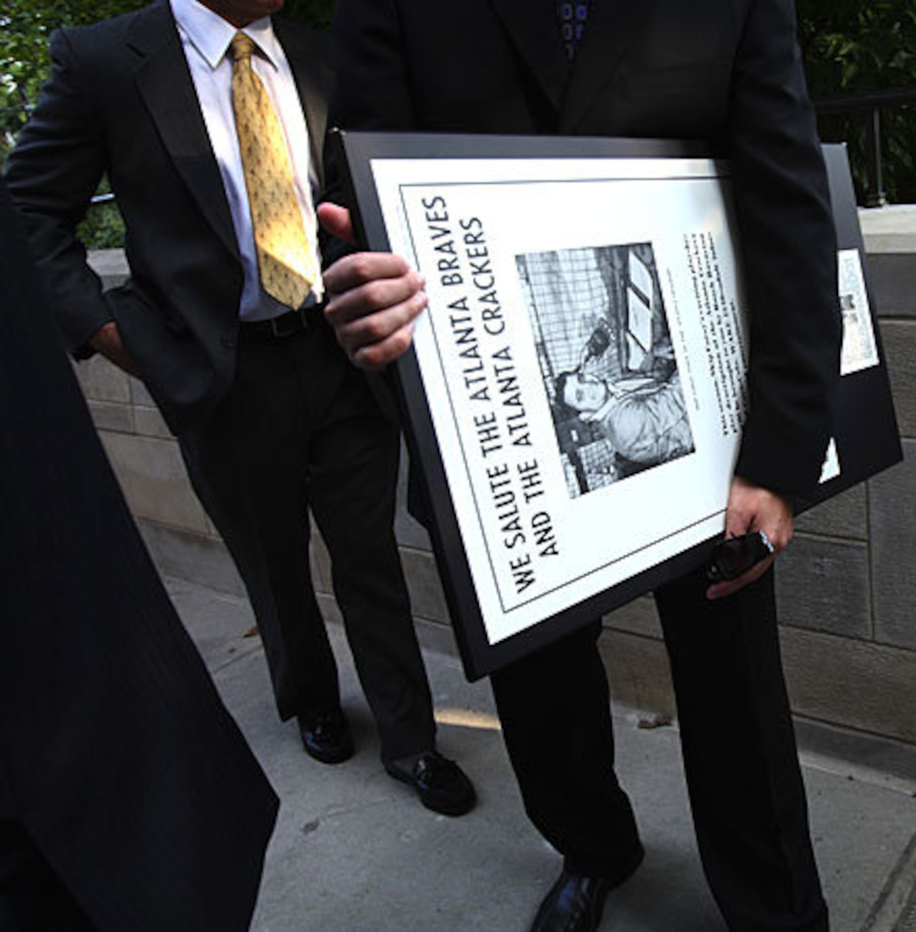 Jeremy Levin, who works at Turner South, carries a Skip Caray newspaper ad from 1965 after Monday's services.