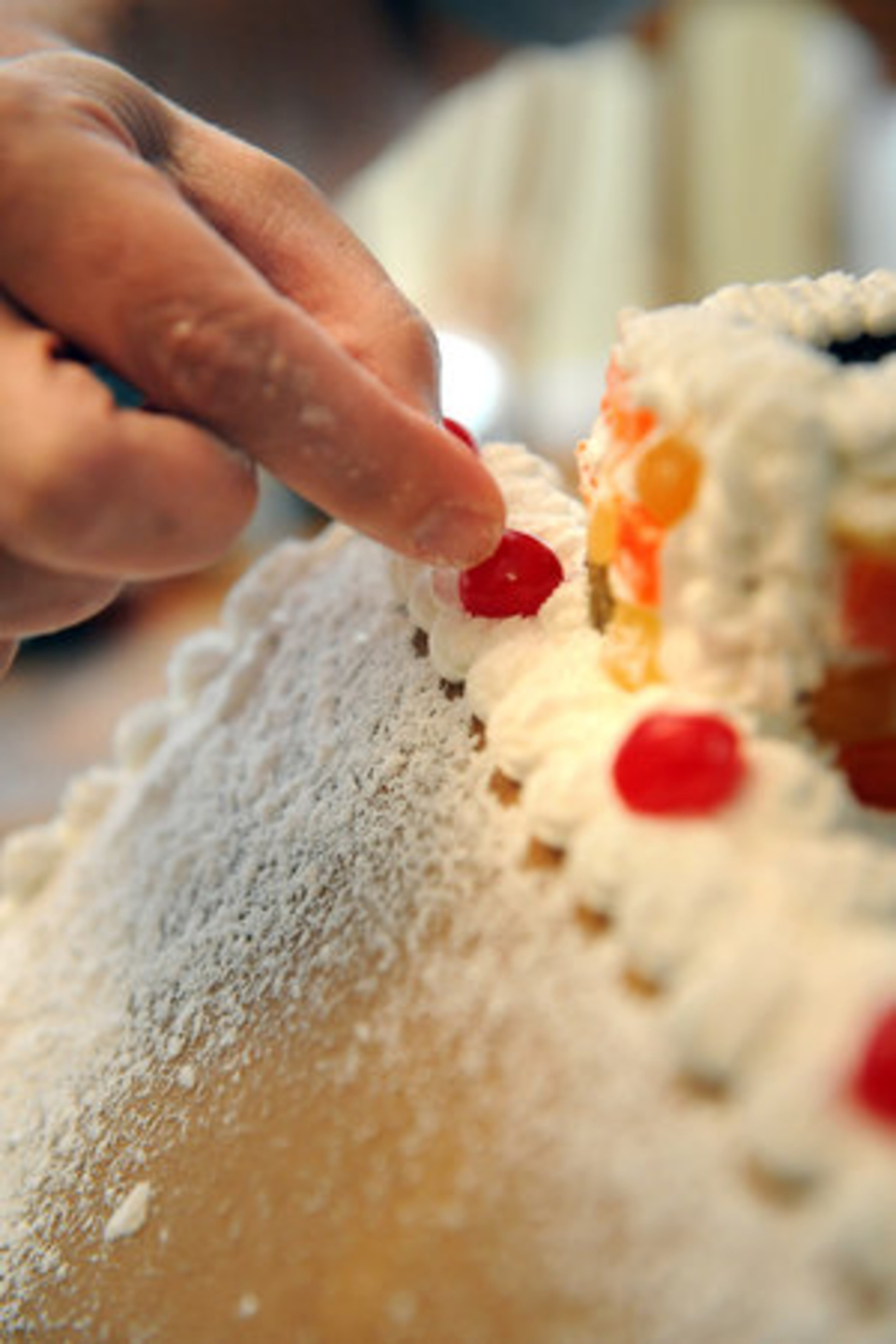 9. After sifting, place cherry candies in the icing border along the edge of the roof. HYOSUB SHIN / HSHIN@AJC.COM