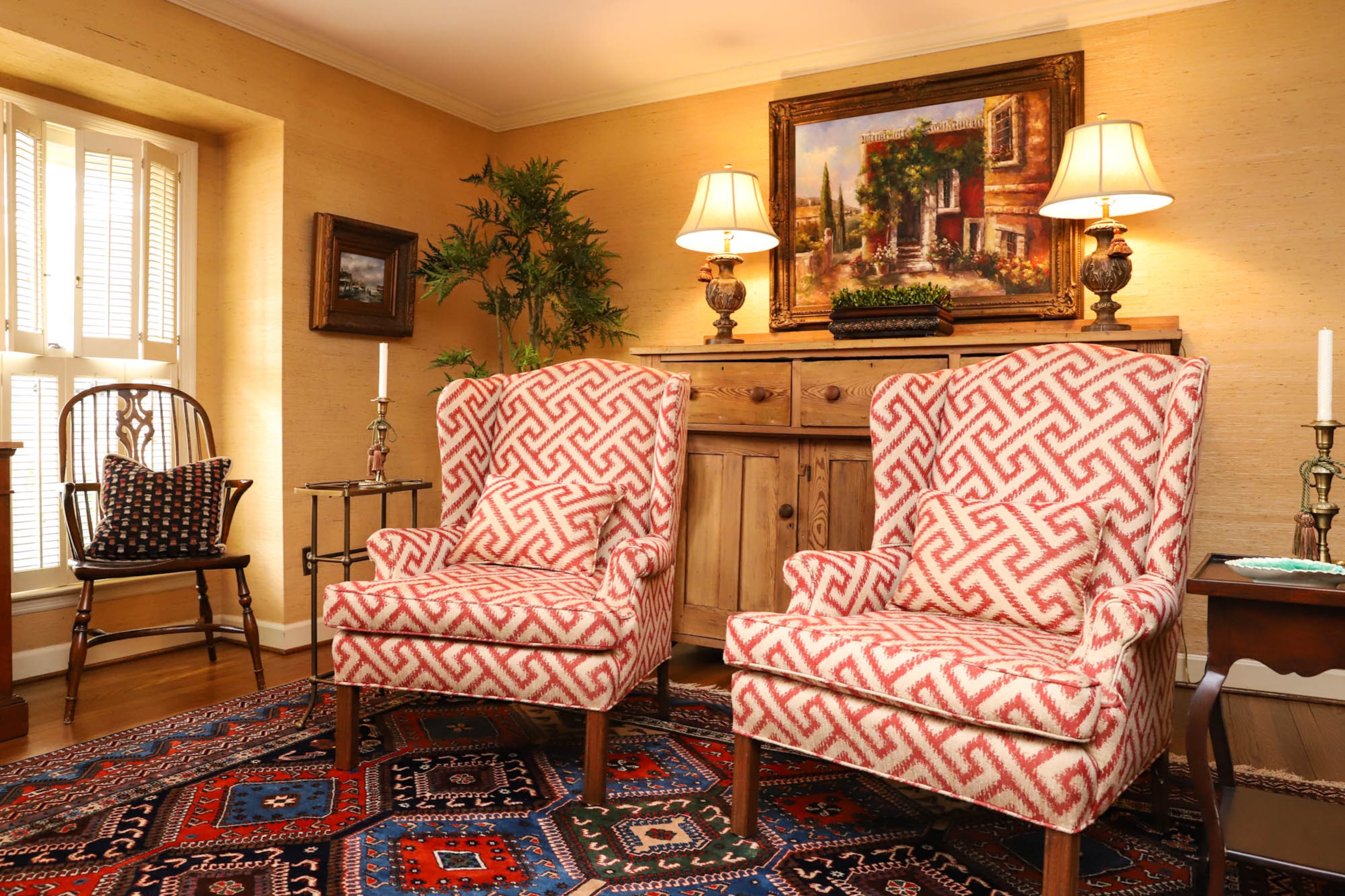 Wingback chairs, which Jane and Leo Carlton purchased in the late '60s from Tidwell Furniture and Decor, create part of the cozy sitting area in the living room of their home. A heart pine credenza that the couple inherited from friends sits along one wall, topped with Glynn lamps, and above the credenza hangs a city scene painting from Scott Antique Markets. Text by Shannon Dominy/Photo by Reynolds Rogers