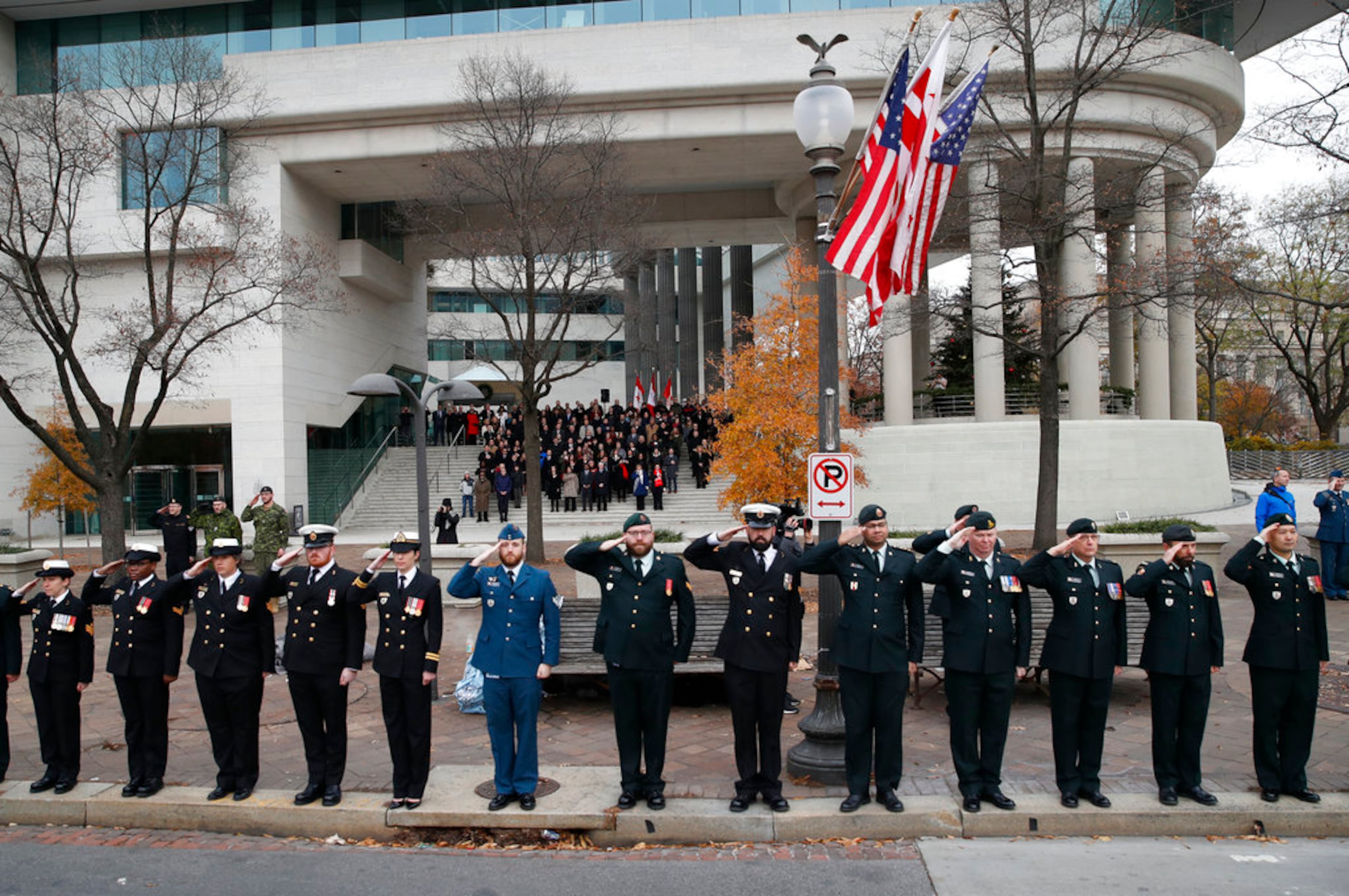 Canadian military salute on the sidewalk outside the Canadian Embassy, as the hearse carrying the flag-draped casket of former President George H.W. Bush drive by on Pennsylvania Ave. from the Capitol to a State Funeral at the National Cathedral, Wednesday, Dec. 5, 2018, in Washington. (AP Photo/Alex Brandon, Pool)