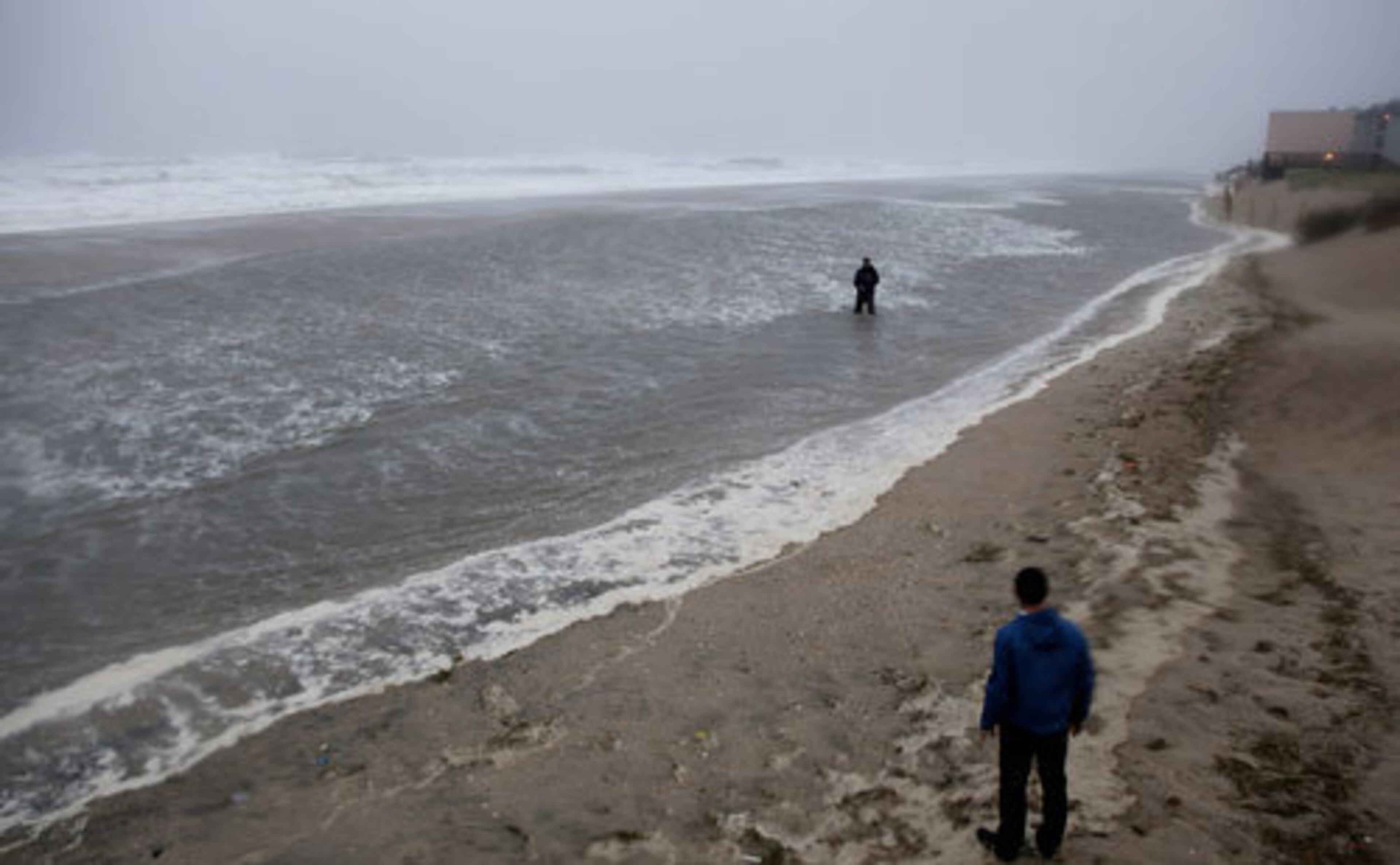 A reporter stands in the water in Nags Head, N.C., Saturday, Aug. 27, 2011, as Hurricane Irene approaches.