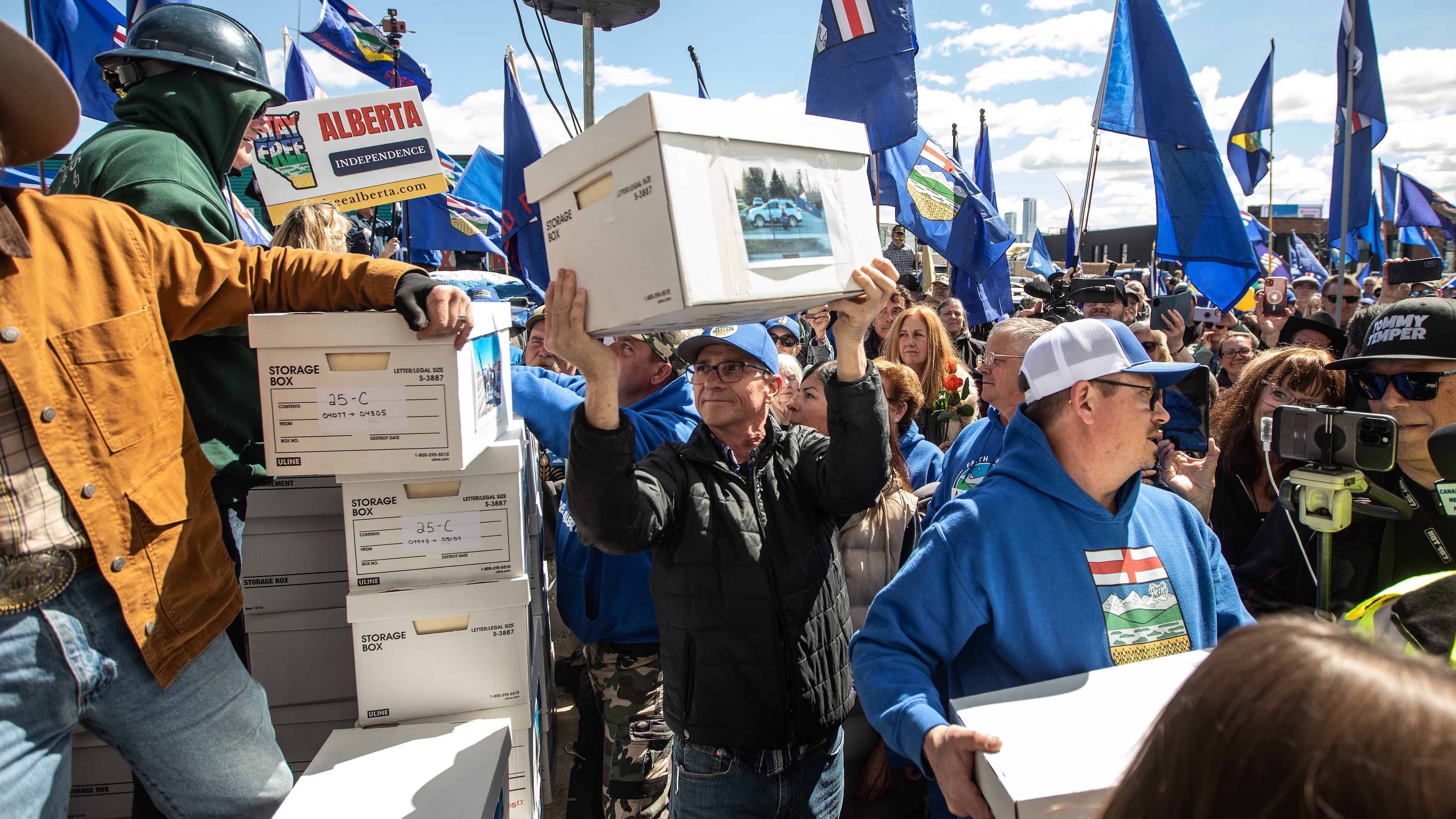 Supporters carry boxes of signatures to submit for a separation referendum to Elections Alberta in Edmonton, on Monday, May 4, 2026. (Jason Franson/The Canadian Press via AP)
