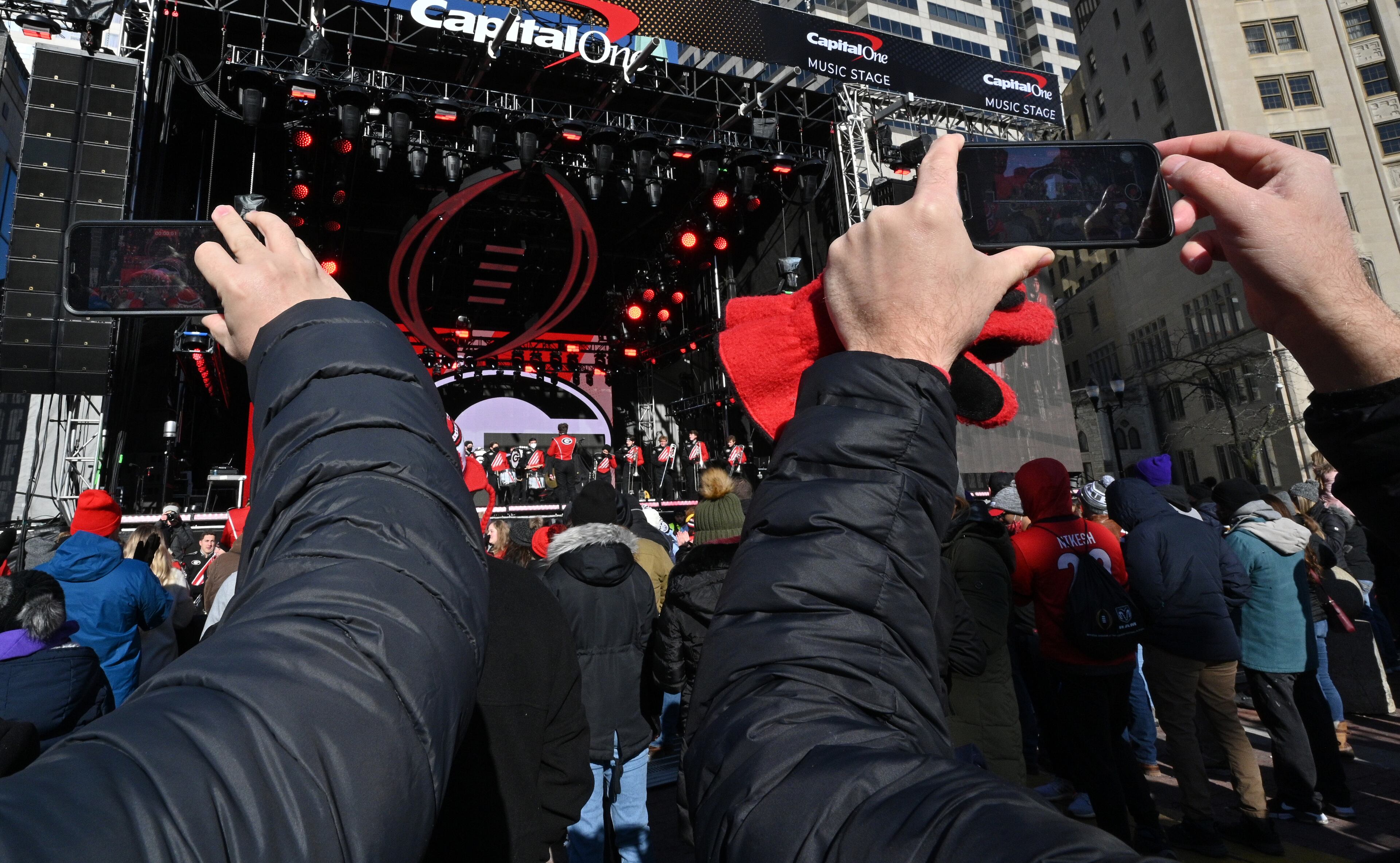 Georgia fans hold their smartphones to take photos as Georgia Redcoat Marching Band performs during Allstate Championship Tailgate event at Monument Circle prior to the 2022 College Football Playoff National Championship Game at Lucas Oil Stadium in Indianapolis on Monday, January 10, 2022. (Hyosub Shin / Hyosub.Shin@ajc.com)