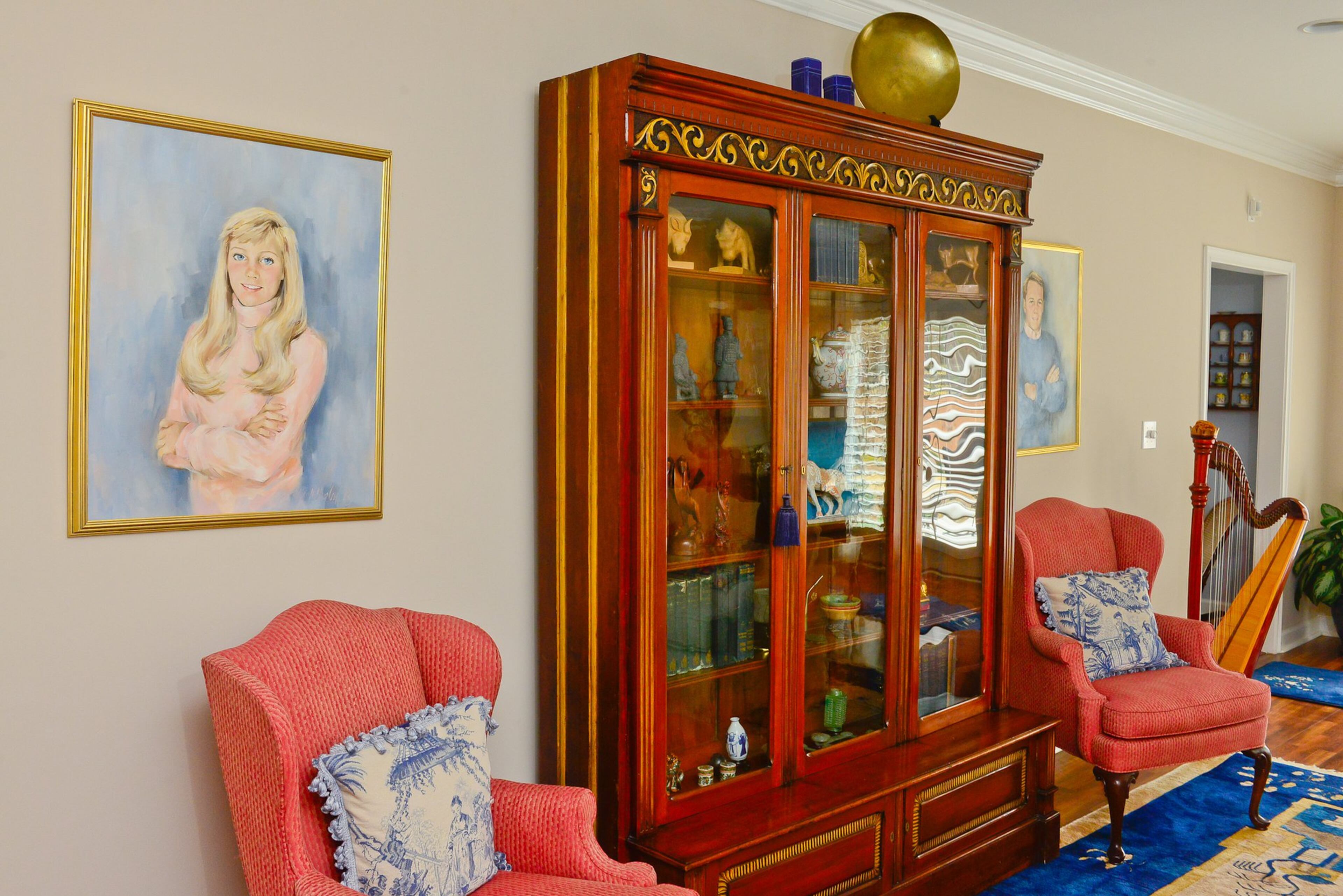 The antique curio cabinet standing in the great room has been passed down through three generations of Chris' family. It was originally a display case in an English shop. On either side of the cabinet hang oil paintings of Chris and Linda's children - their son when he was 21 and their daughter when she was 18.