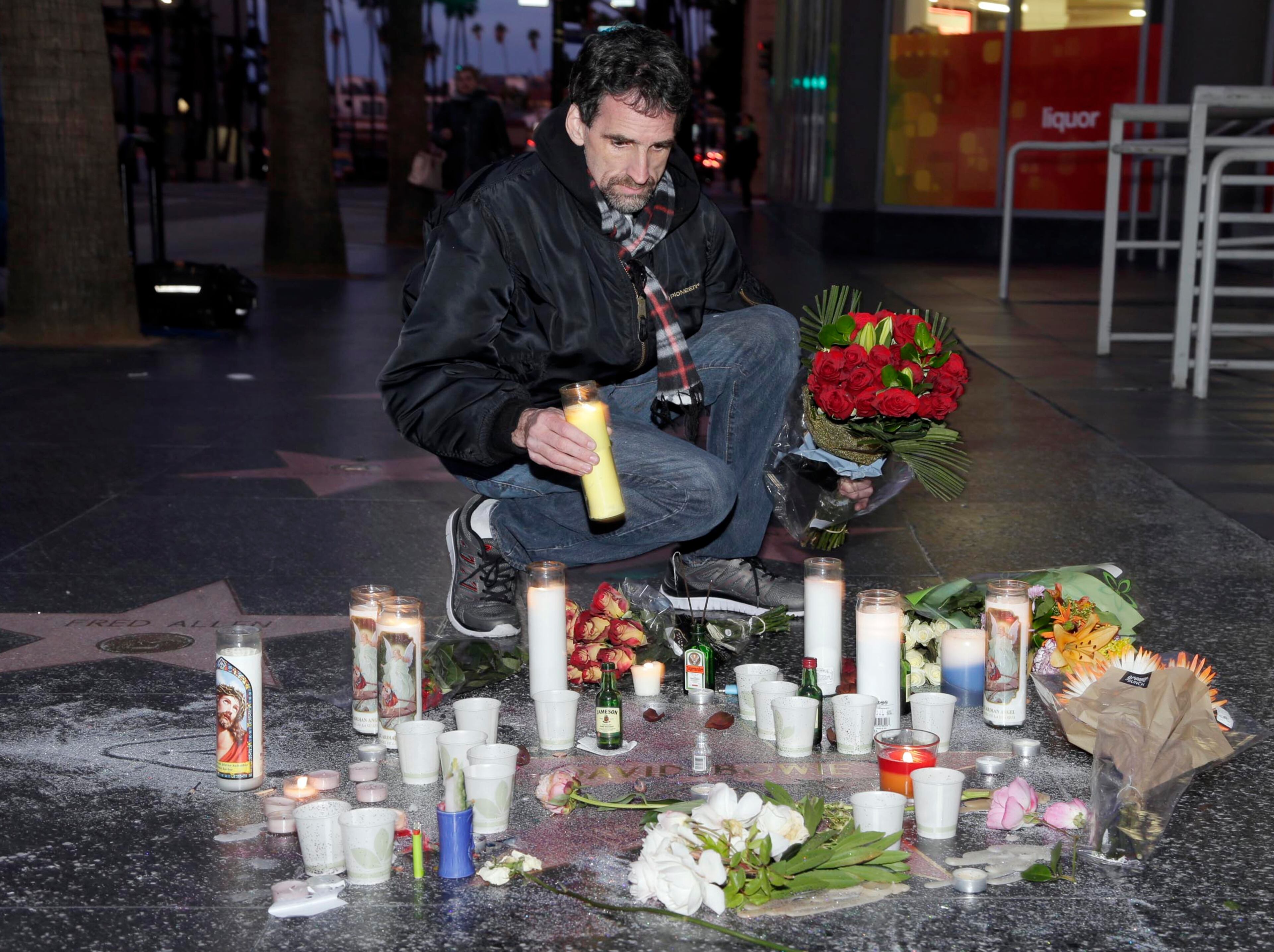 A mourner leaves a candle at a makeshift memorial at David Bowie's star on the Hollywood Walk of Fame in Los Angeles, Monday, Jan. 11, 2016. Bowie, the other-worldly musician who broke pop and rock boundaries with his creative musicianship, nonconformity, striking visuals and a genre-spanning persona he christened Ziggy Stardust, died of cancer Sunday. He was 69 and had just released a new album. (AP Photo/Nick Ut)