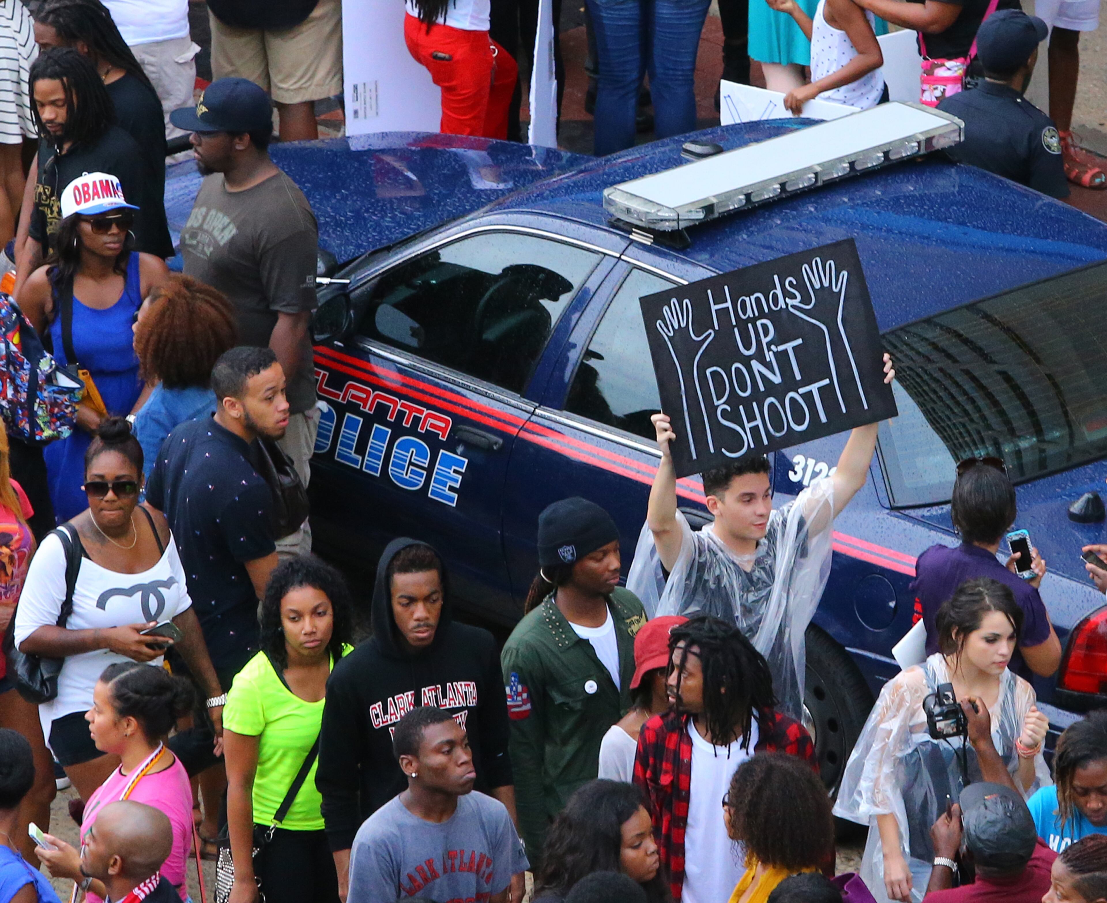 081814 Atlanta: Protesters pass by an Atlanta police vehicle during a rally for Mike Brown and Ferguson outside the CNN Center on Monday, August 18, 2014, in Atlanta. CURTIS COMPTON / CCOMPTON@AJC.COM