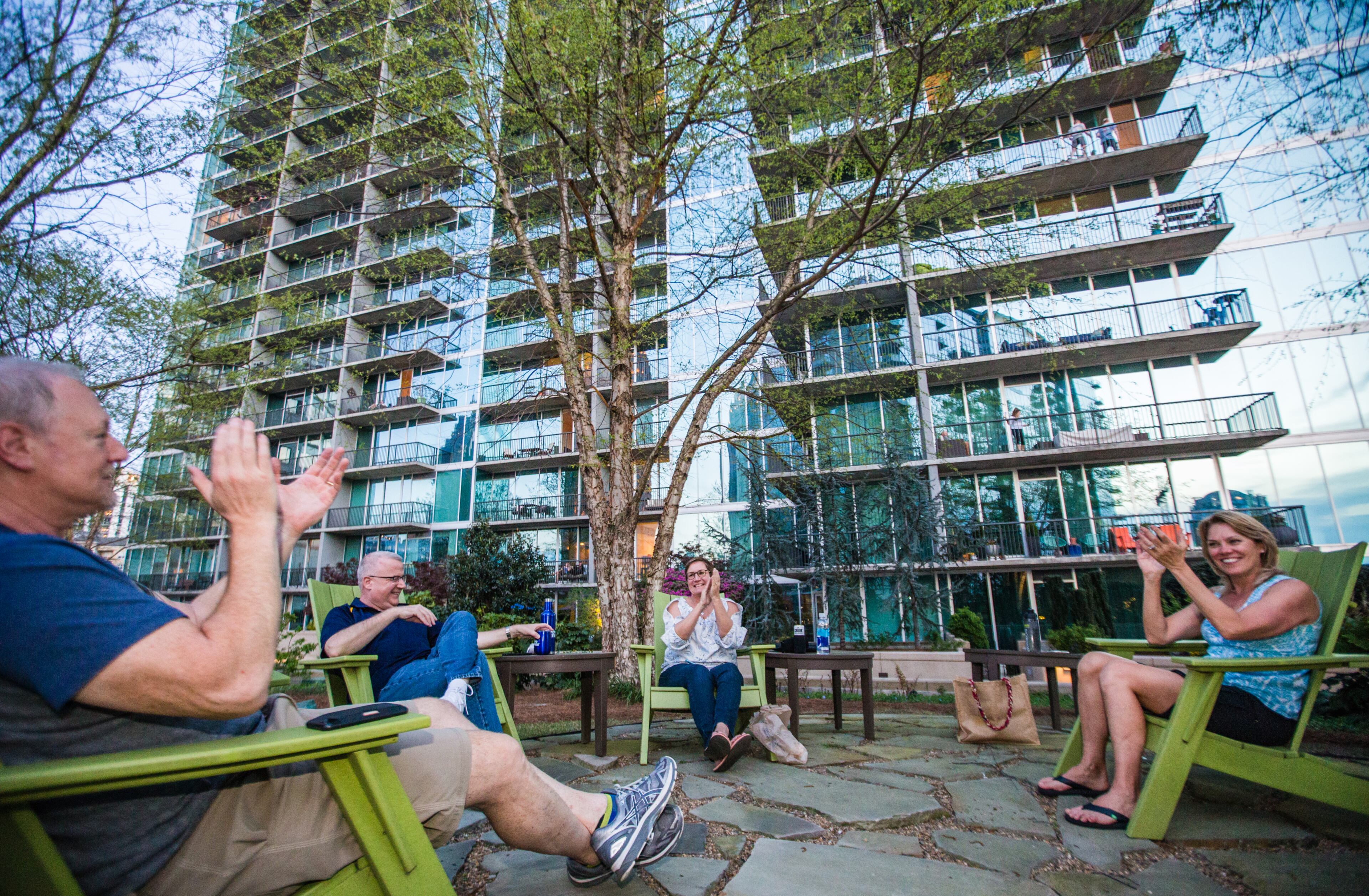 1010 Midtown residents, Mark Furlet, from left, Brian and Loree Rose and Tammy Furlet celebrate first responders at 8 pm on Friday, March 27, 2020. A Nextdoor post suggested the gesture nearly a week ago, after coronavirus disrupted social standards. The high-rise community is prompted by loudspeaker to show support and celebrate those who must keep working. The neighbors along Peachtree and 11th Streets cheer, play music and turn pots and pans into noise makers. (Jenni Girtman for the Atlanta Journal-Constitution)