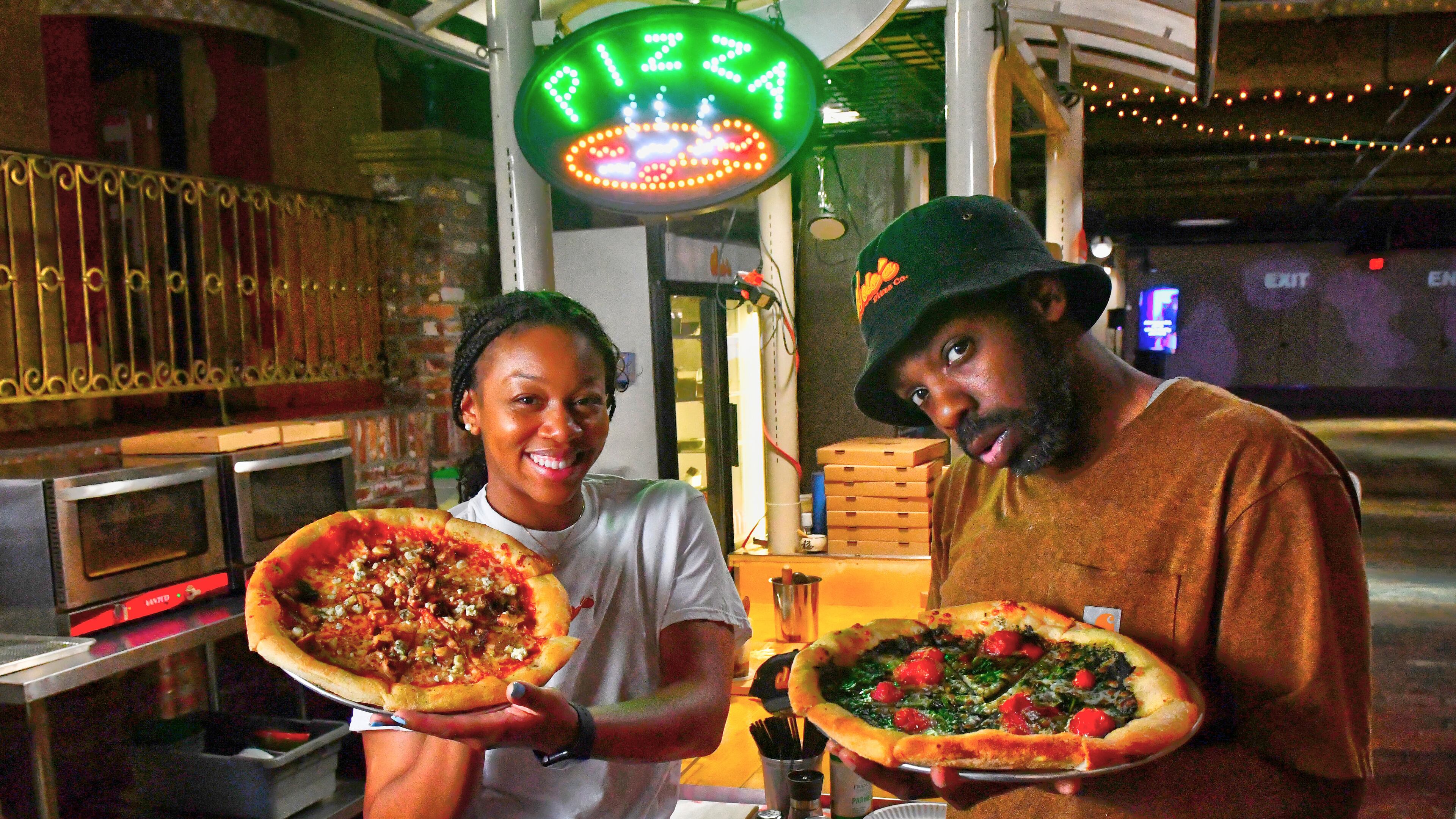 Dolo’s Pizza pop-up in Underground Atlanta, with owners Alyson Williams (left) and Yusef Walker showing off two of their pizzas. (CHRIS HUNT FOR THE ATLANTA JOURNAL-CONSTITUTION)