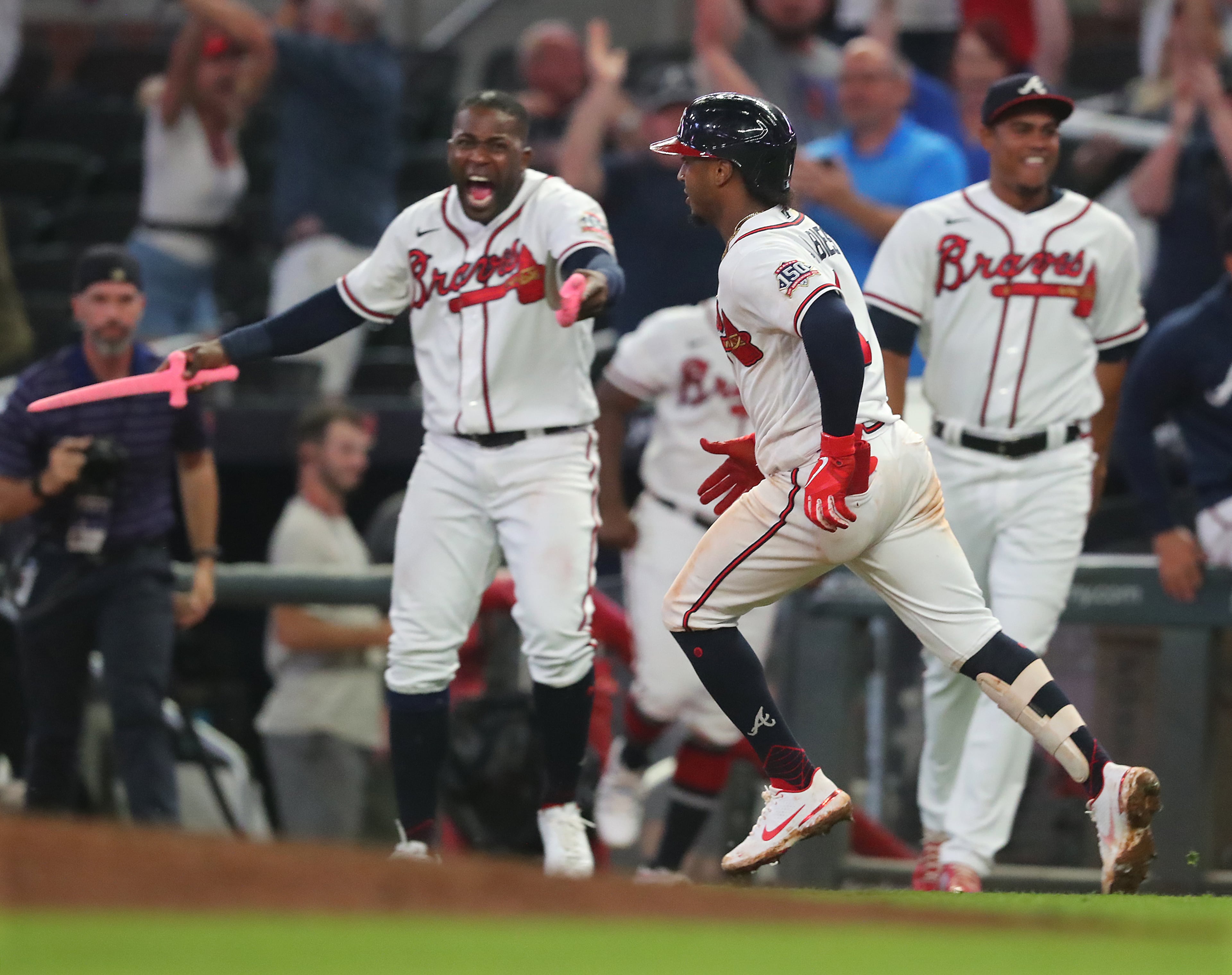 Atlanta Braves outfielder Guillermo Heredia (left) holds a pink sword while cheering second baseman Ozzie Albies as he rounds first base after hitting a 3-run walk-off homer. “Curtis Compton / Curtis.Compton@ajc.com”