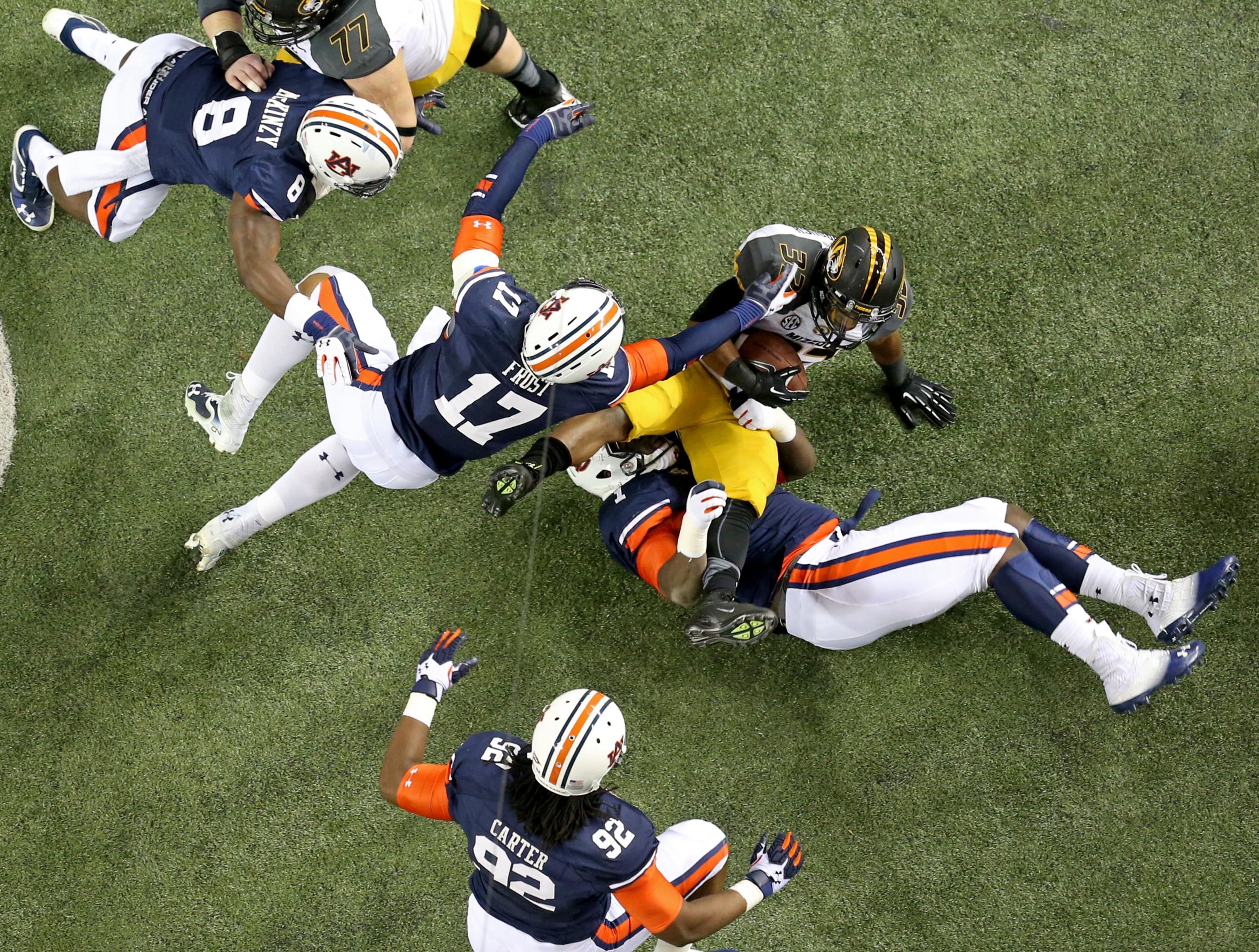 Missouri tailback Russell Hansbrough (32) gets stopped by Auburn defenders Kris Frost (17) and Montravius Adams (1, beneath Hansbrough) for a short run during Auburn's 59-42 win over Missouri in the SEC Championship Saturday night in Atlanta, Ga., December 7, 2013. JASON GETZ / JGETZ@AJC.COM