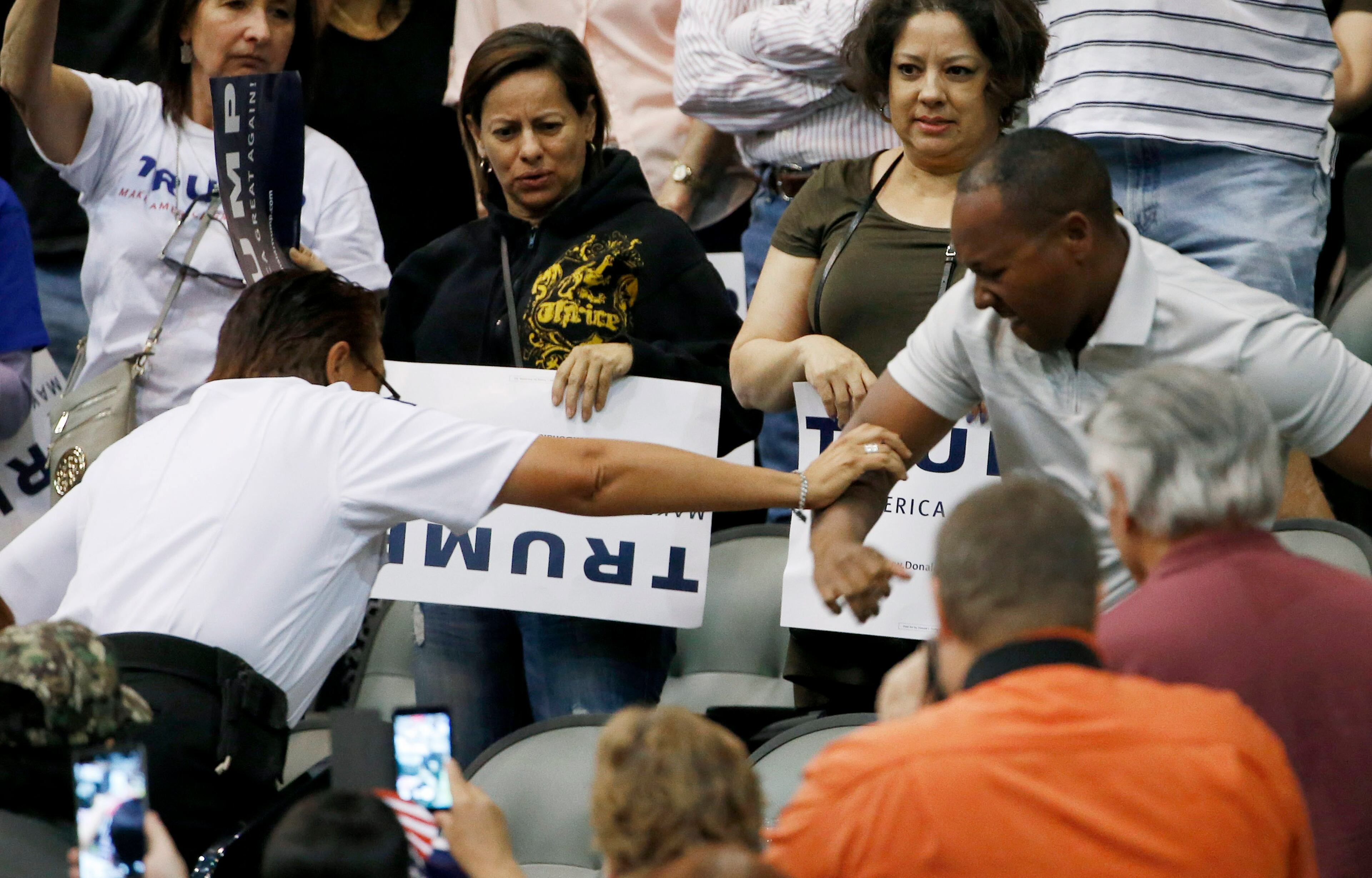 A member of security, left, tries to break up a scuffle between an anti-Donald Trump protester, out of picture, and another person, right, as the Republican presidential candidate was speaking during a campaign rally Saturday, March 19, 2016, in Tucson, Ariz. (AP Photo/Ross D. Franklin)