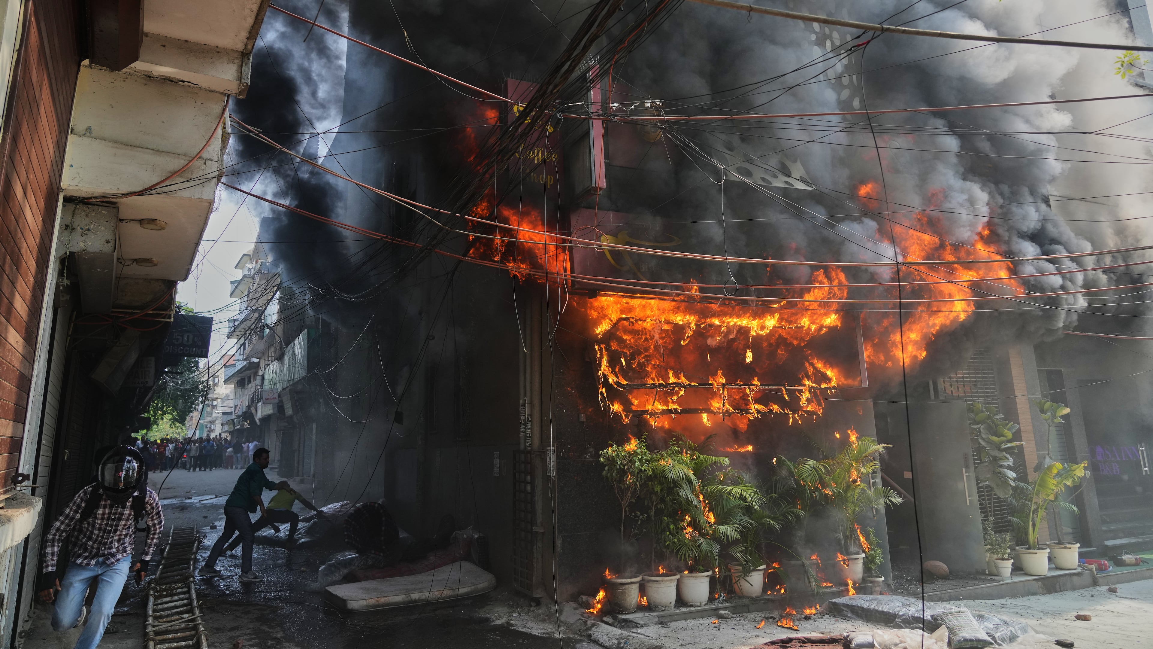 Local people attempt to douse a fire at a hotel in New Delhi, India, Wednesday, June 3, 2026. (AP Photo/Manish Swarup)