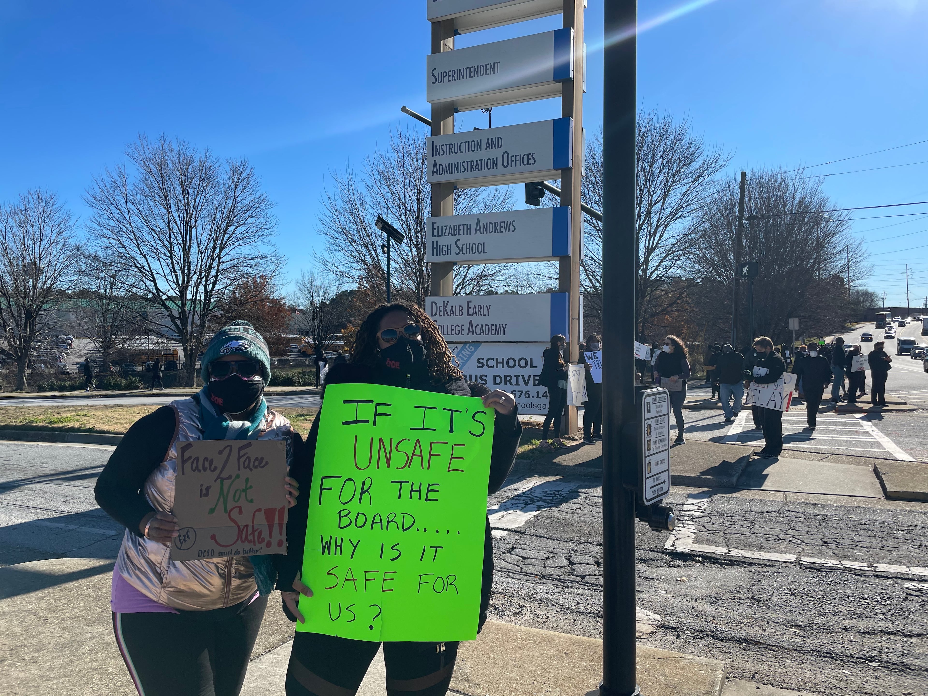 Community members in DeKalb held signs on Tuesday to protest against the reopening of DeKalb County schools.