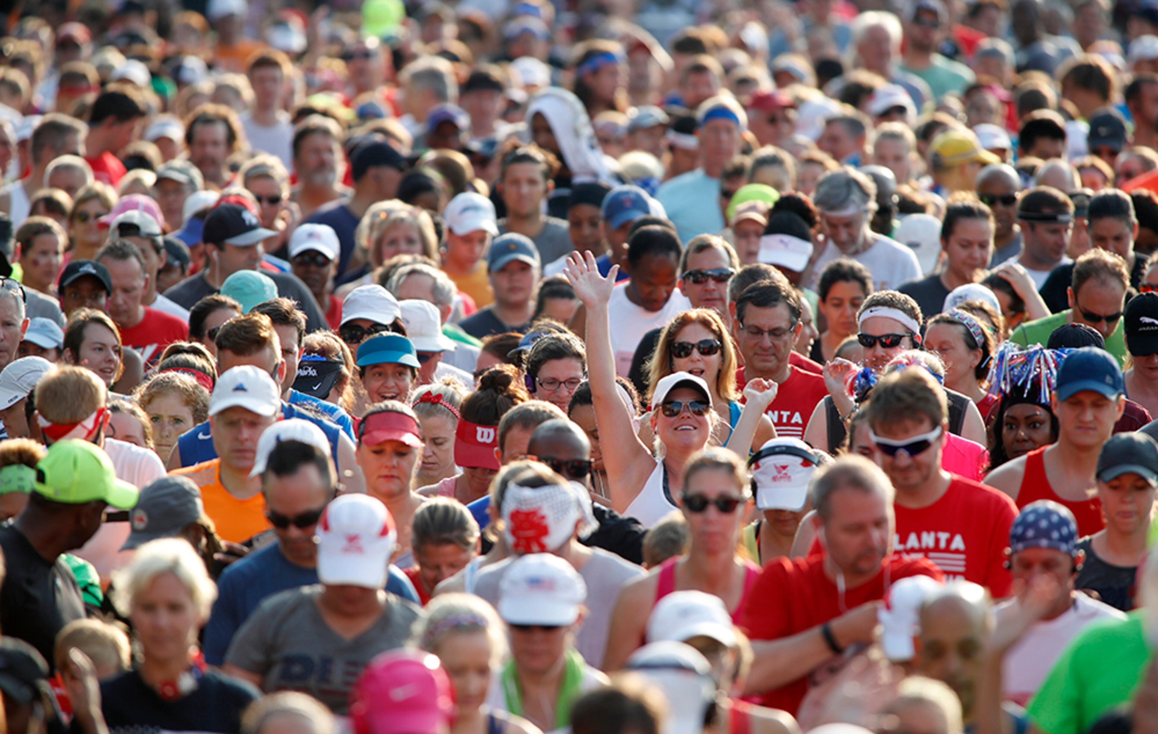 A runner waves as she and others cross the starting line of the 47th running of the AJC Peachtree Road Race Monday July 4, 2016, in Atlanta.
