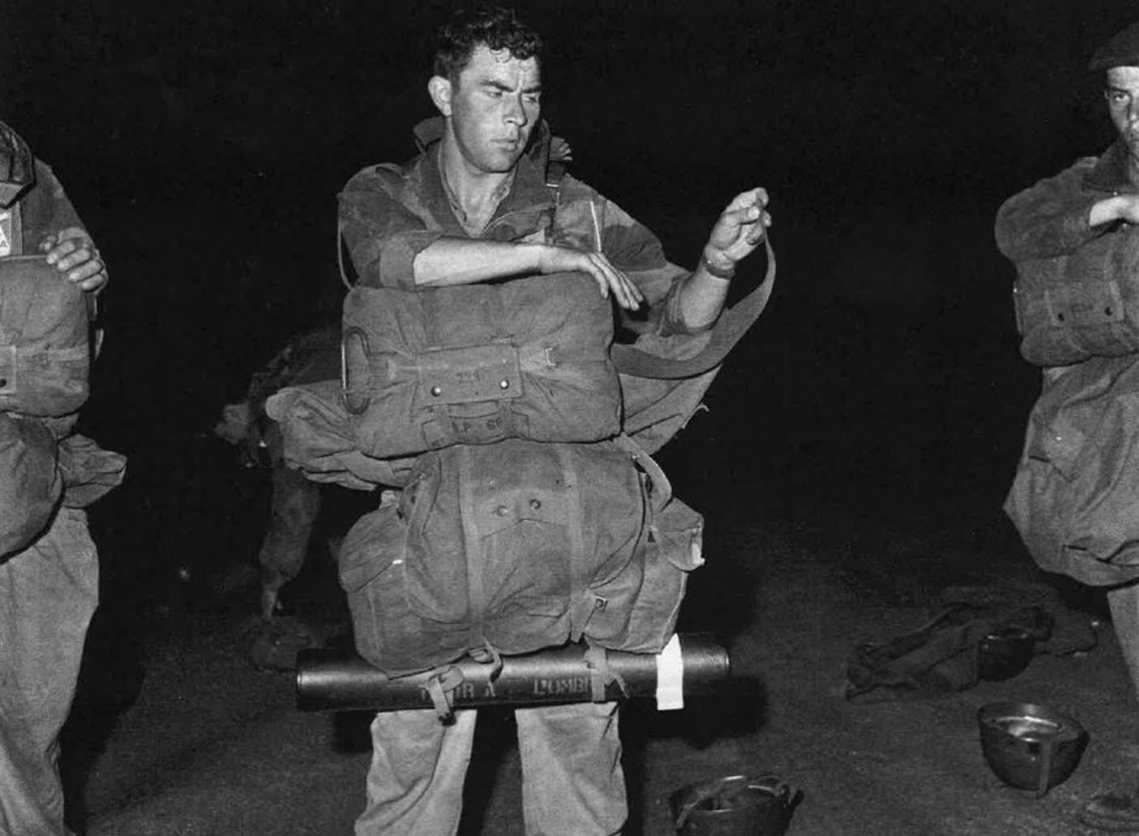 This Belgian paratrooper checks his equipment in the predawn darkness at an abandoned airfield in Kamina, south of Stanleyville, where the joint force staged its operation.