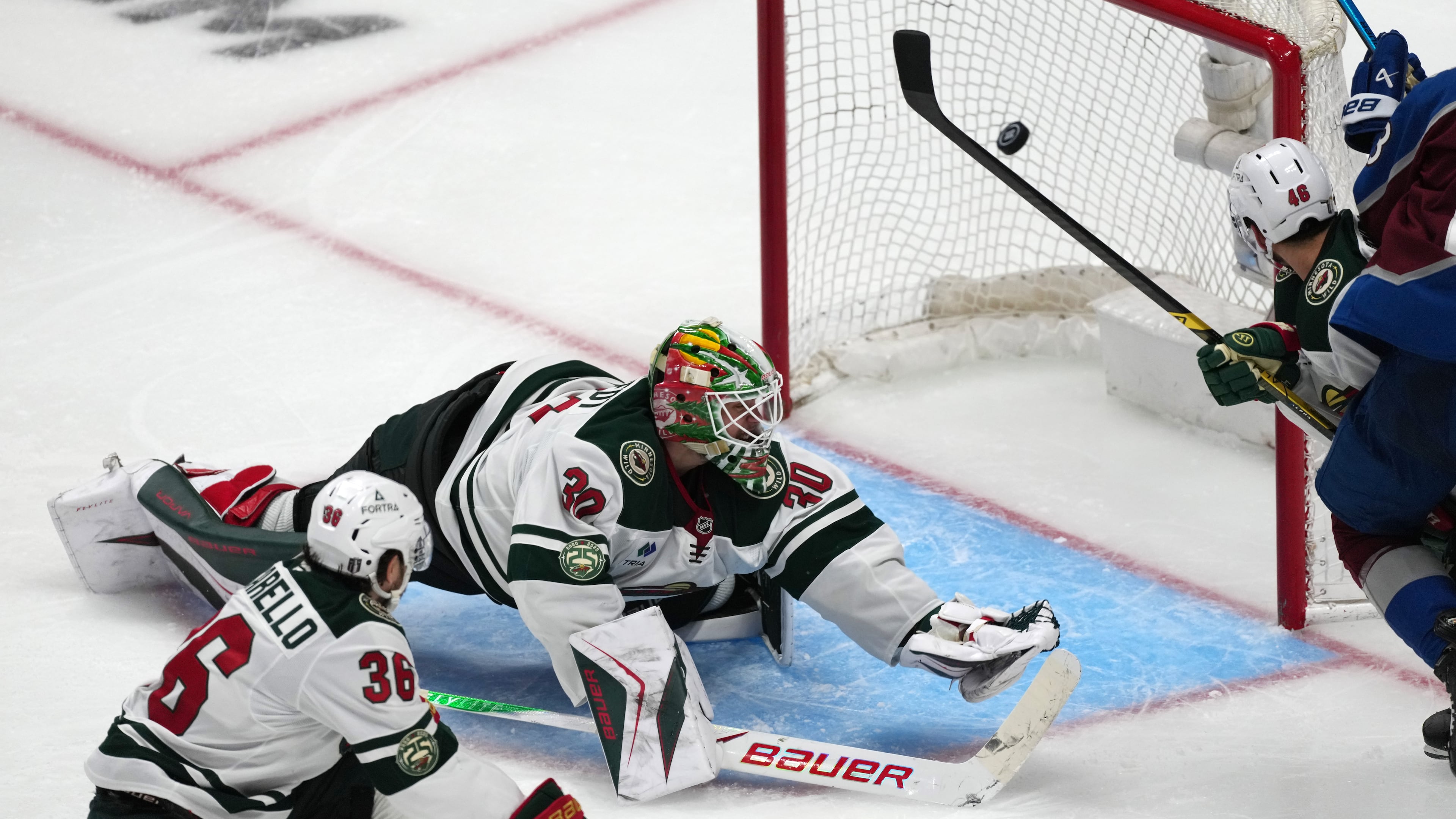 Minnesota Wild goaltender Jesper Wallstedt, center, misses a goal shot by Colorado Avalanche defenseman Brett Kulak as Minnesota right wing Mats Zuccarello, left, and defenseman Jared Spurgeon cover in overtime of Game 5 of an NHL Stanley Cup hockey second-round playoff series Wednesday, May 13, 2026, in Denver. (AP Photo/David Zalubowski)