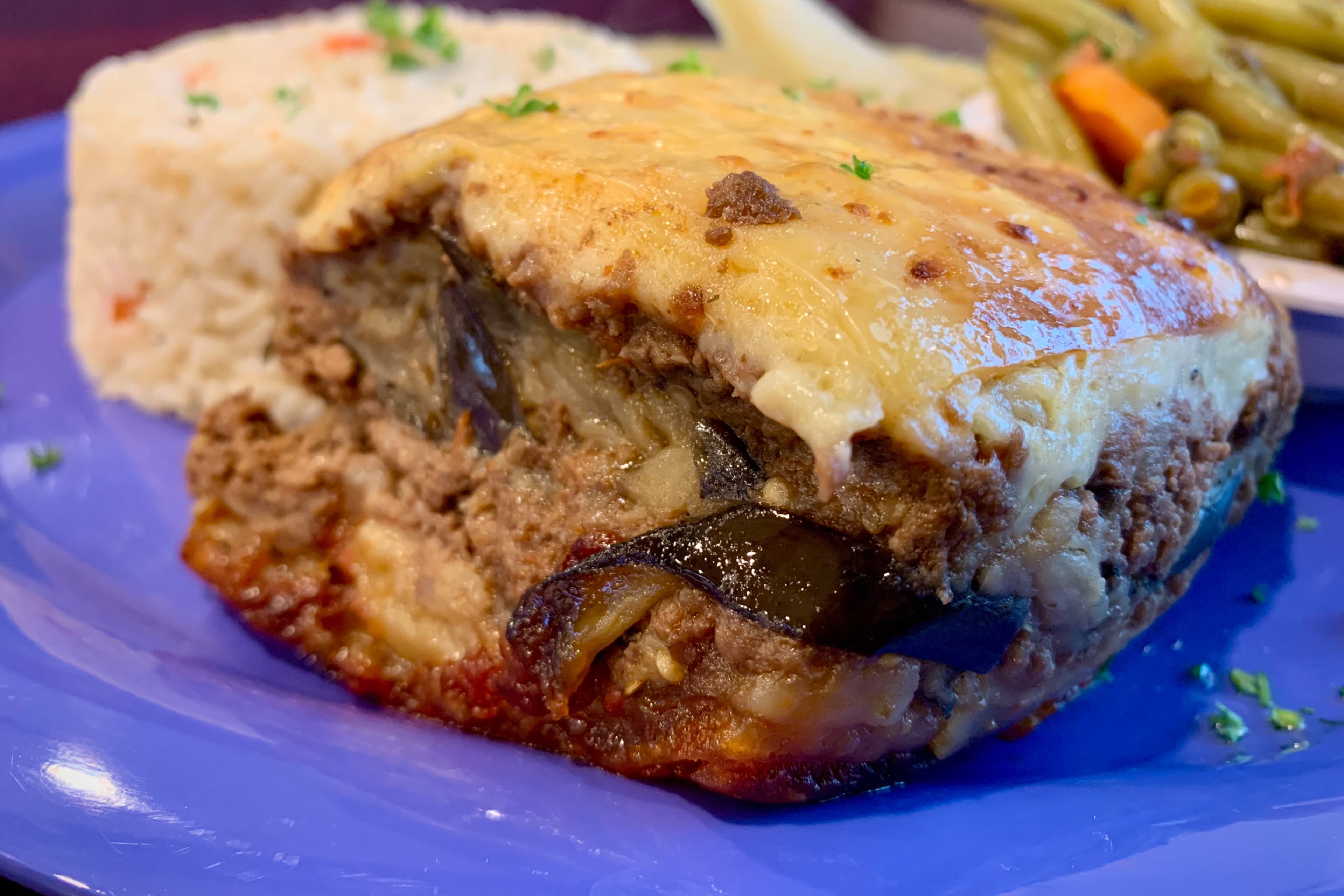 Marietta restaurant It’s Greek to Us rounds out its platter of moussaka with lemony, oregano-flecked Greek potatoes and garlicky green beans. (Christopher Hassiotis for the AJC)