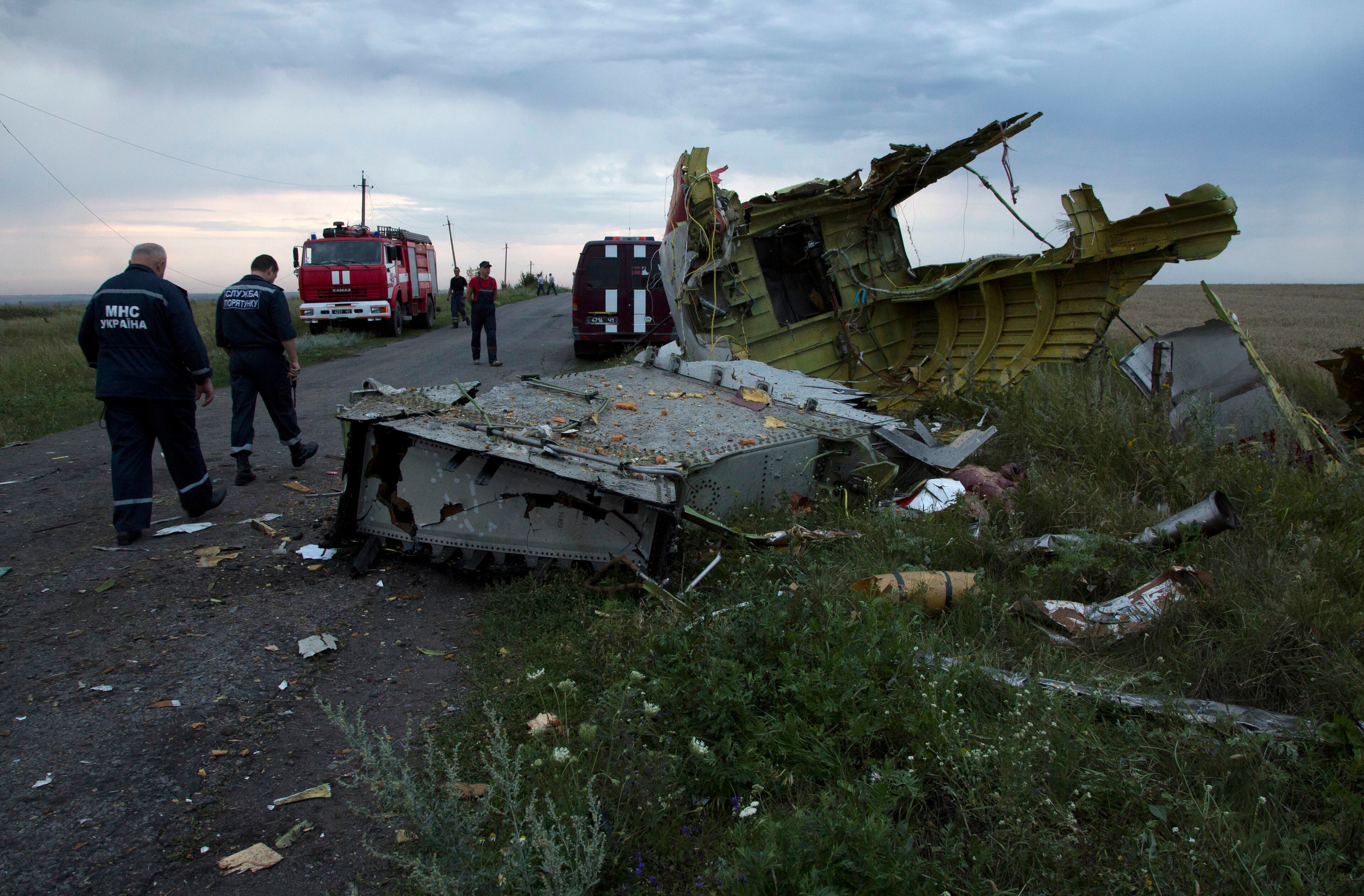 Ukrainian rescuers walk past debris at the crash site of a passenger plane near the village of Grabovo, Ukraine, Thursday, July 17, 2014. Ukraine said a passenger plane carrying 295 people was shot down Thursday as it flew over the country, and both the government and the pro-Russia separatists fighting in the region denied any responsibility for downing the plane. (AP Photo/Dmitry Lovetsky)